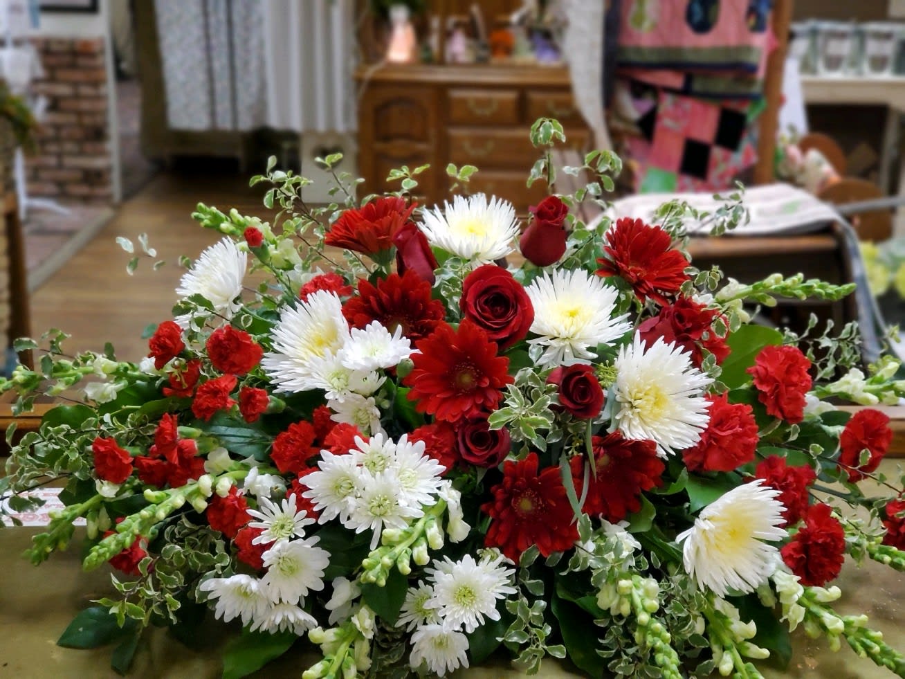 Low floral arrangement of red and white flowers with greenery