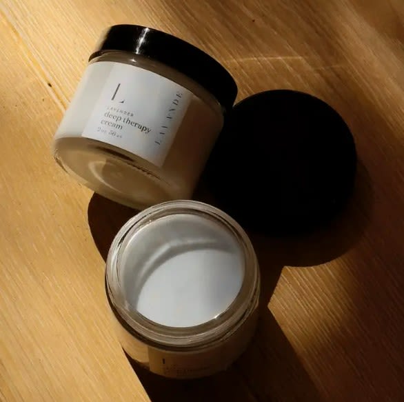 Two cosmetic cream jars with black lids on a wooden surface