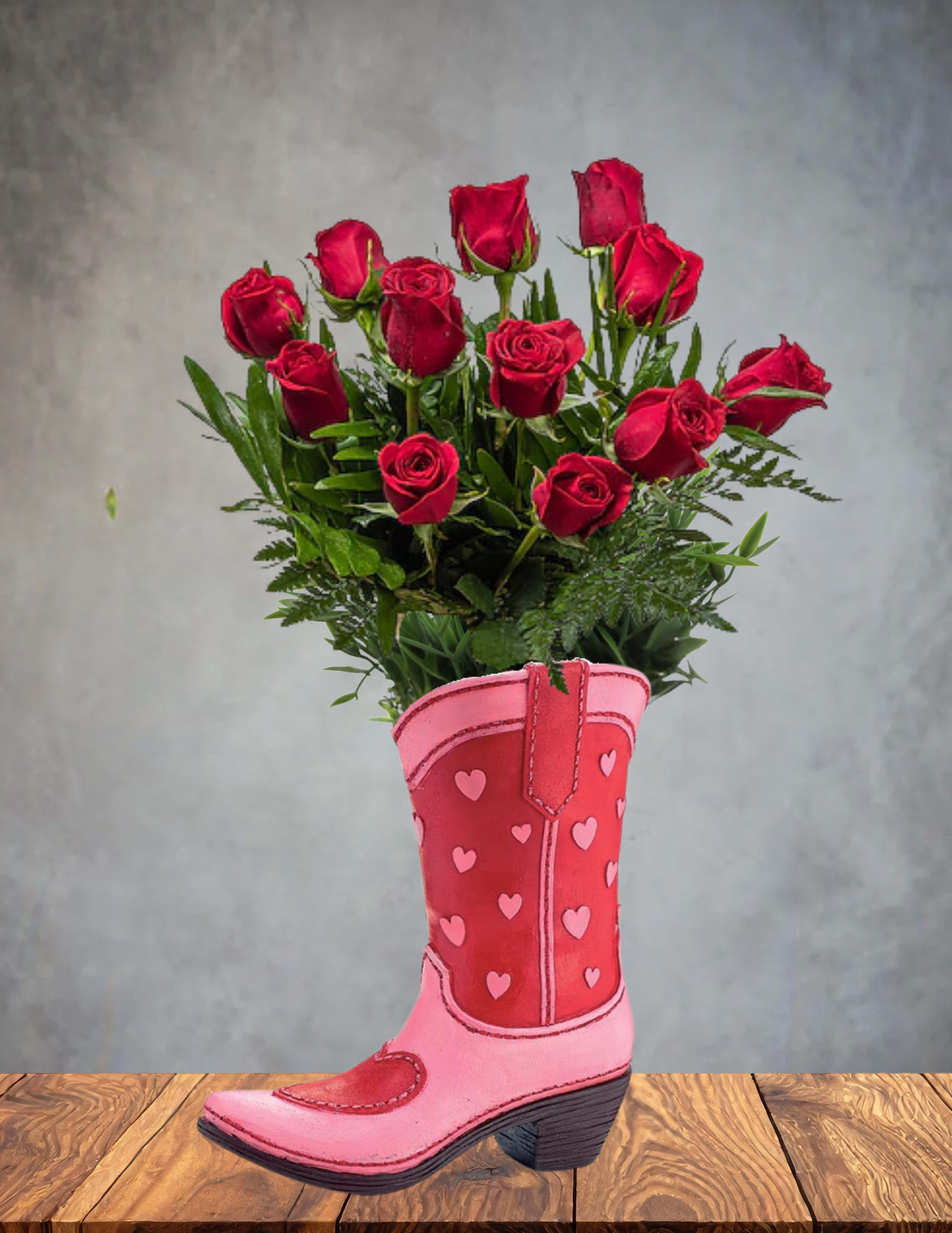 Red roses arranged in a pink cowboy boot vase with heart accents