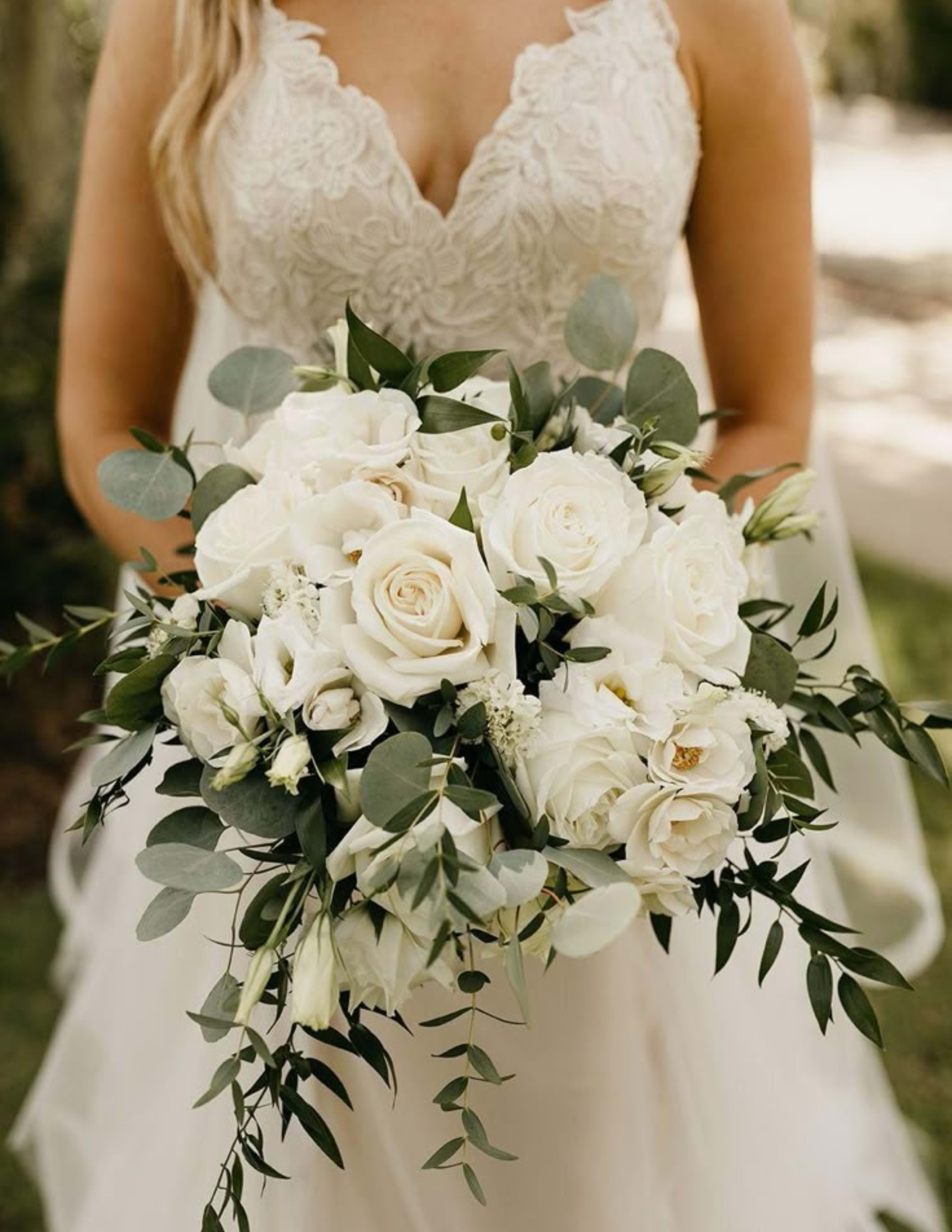 Bride holding a white rose bouquet with greenery