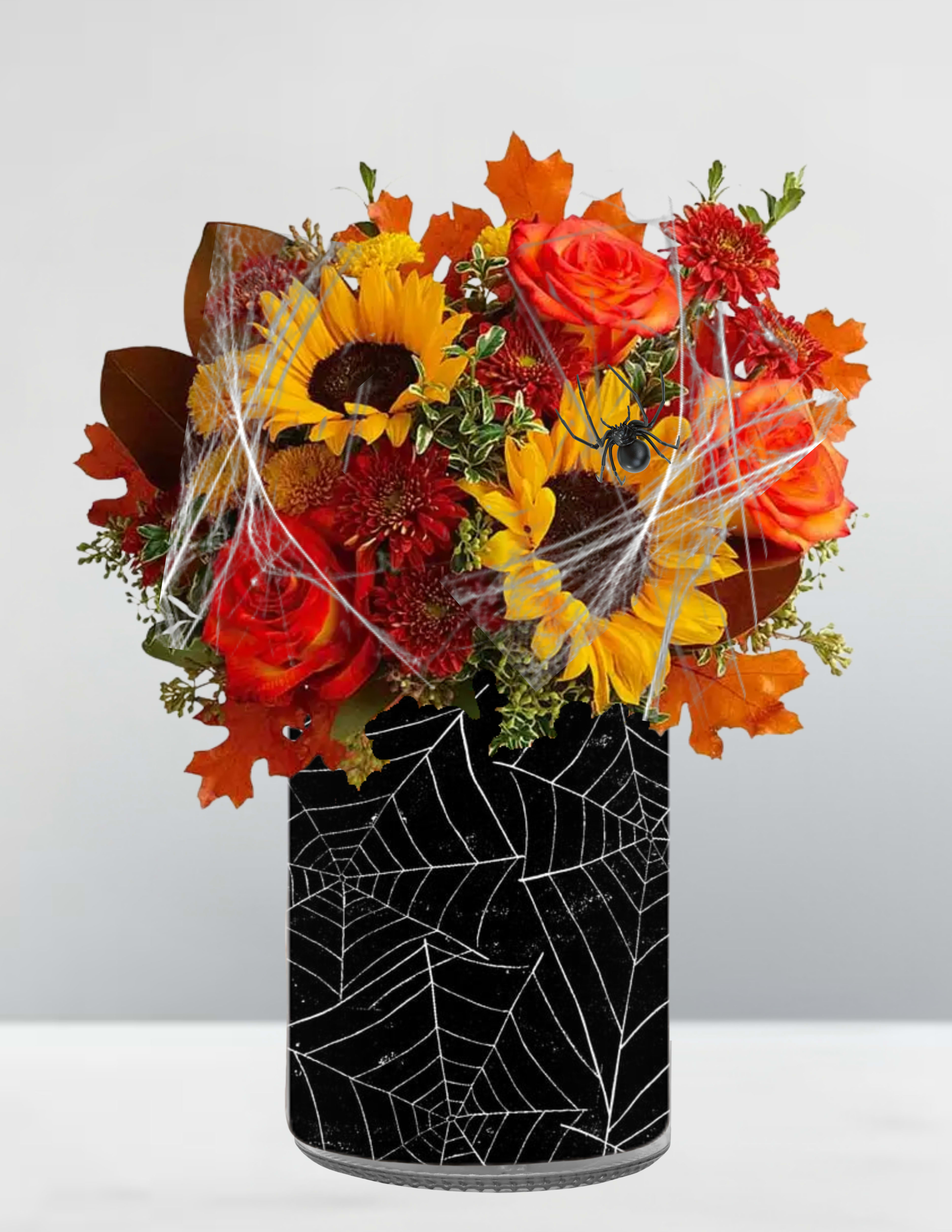 Spooky cauldron surprise  - Spooky Cauldron Surprise Double, double, bloom and bubble—this festive fright is brewing with autumn magic. Nestled in a glossy black cauldron spun with spider webs and creepy crawlers, vibrant sunflowers, fiery roses, and fall foliage burst forth like a spell gone delightfully rogue. Wisps of faux cobwebs and mischievous spiders weave through the blooms, adding just the right touch of haunted charm. Whether casting a spell on your entryway or conjuring smiles at a Halloween bash, Spooky Cauldron Surprise is wickedly whimsical and eerily elegant.