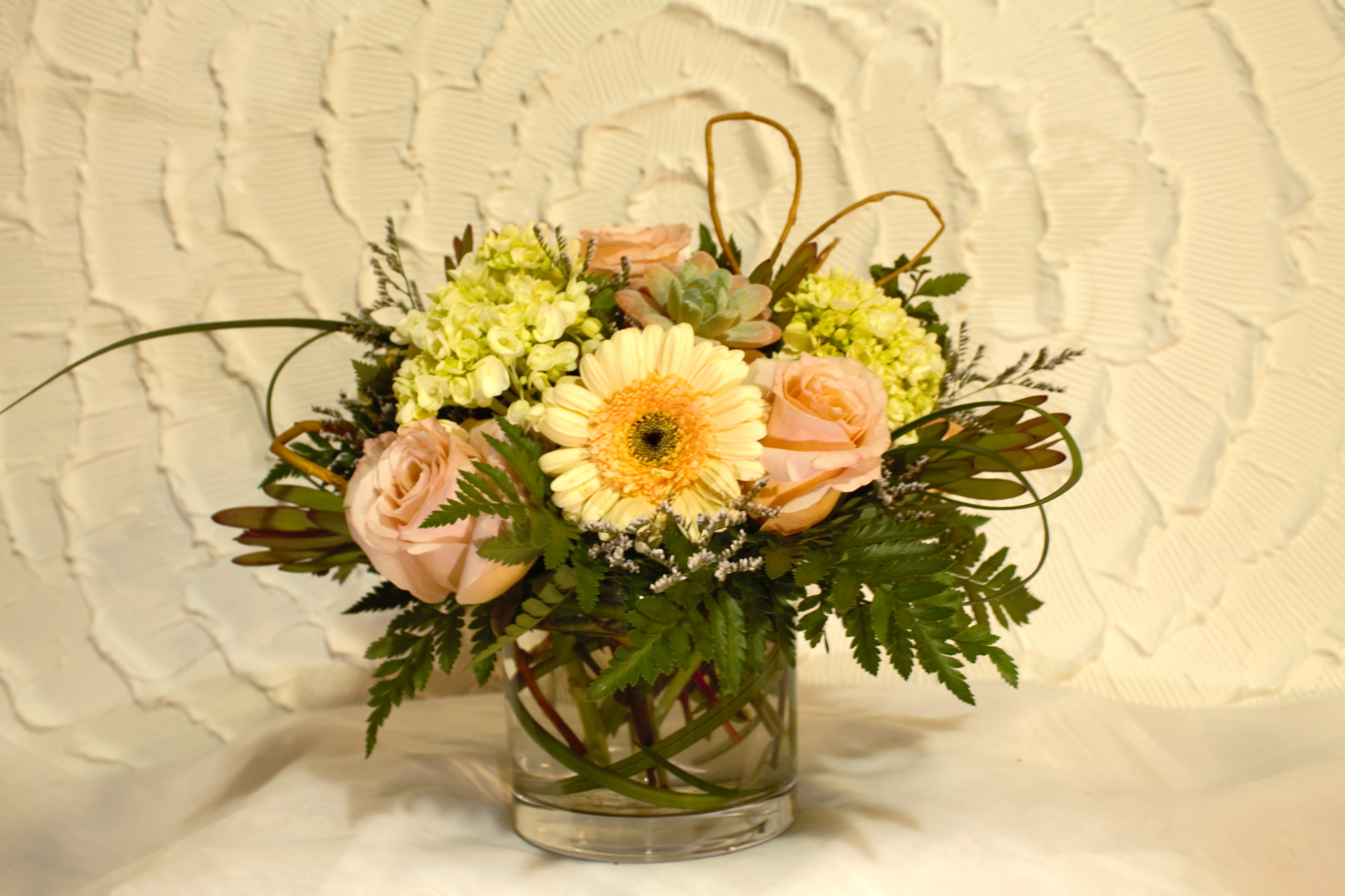 Bouquet of pale pink roses and a peach gerbera daisy in a glass vase