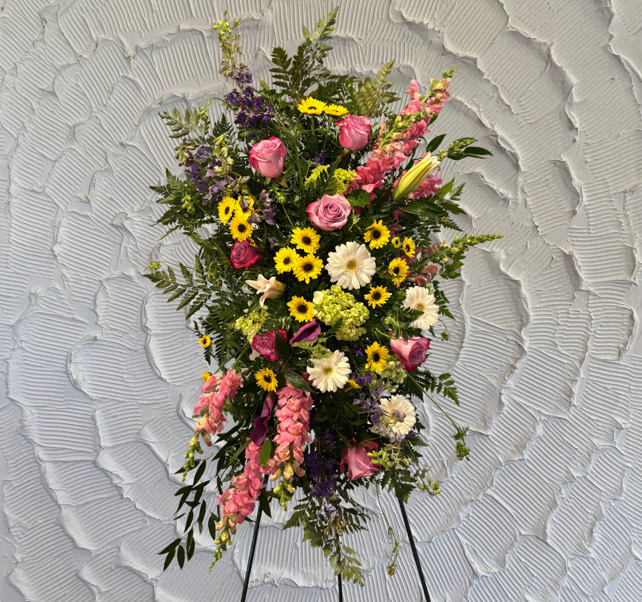 Standing floral spray with pink roses, yellow daisies, and purple blooms