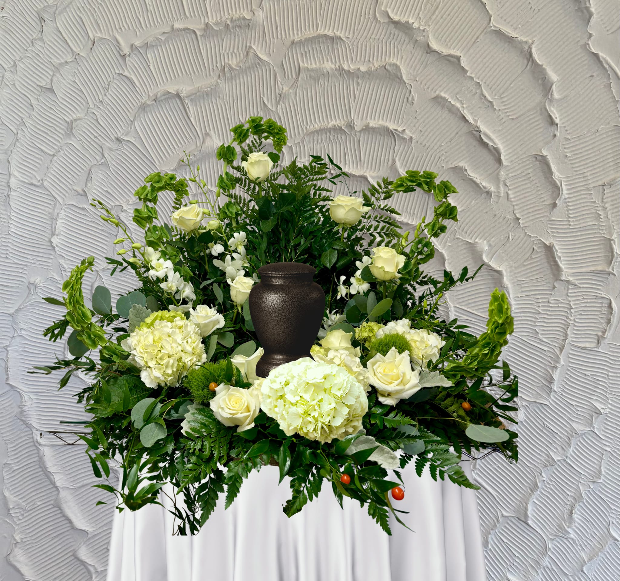 White floral funeral arrangement with a dark urn centerpiece