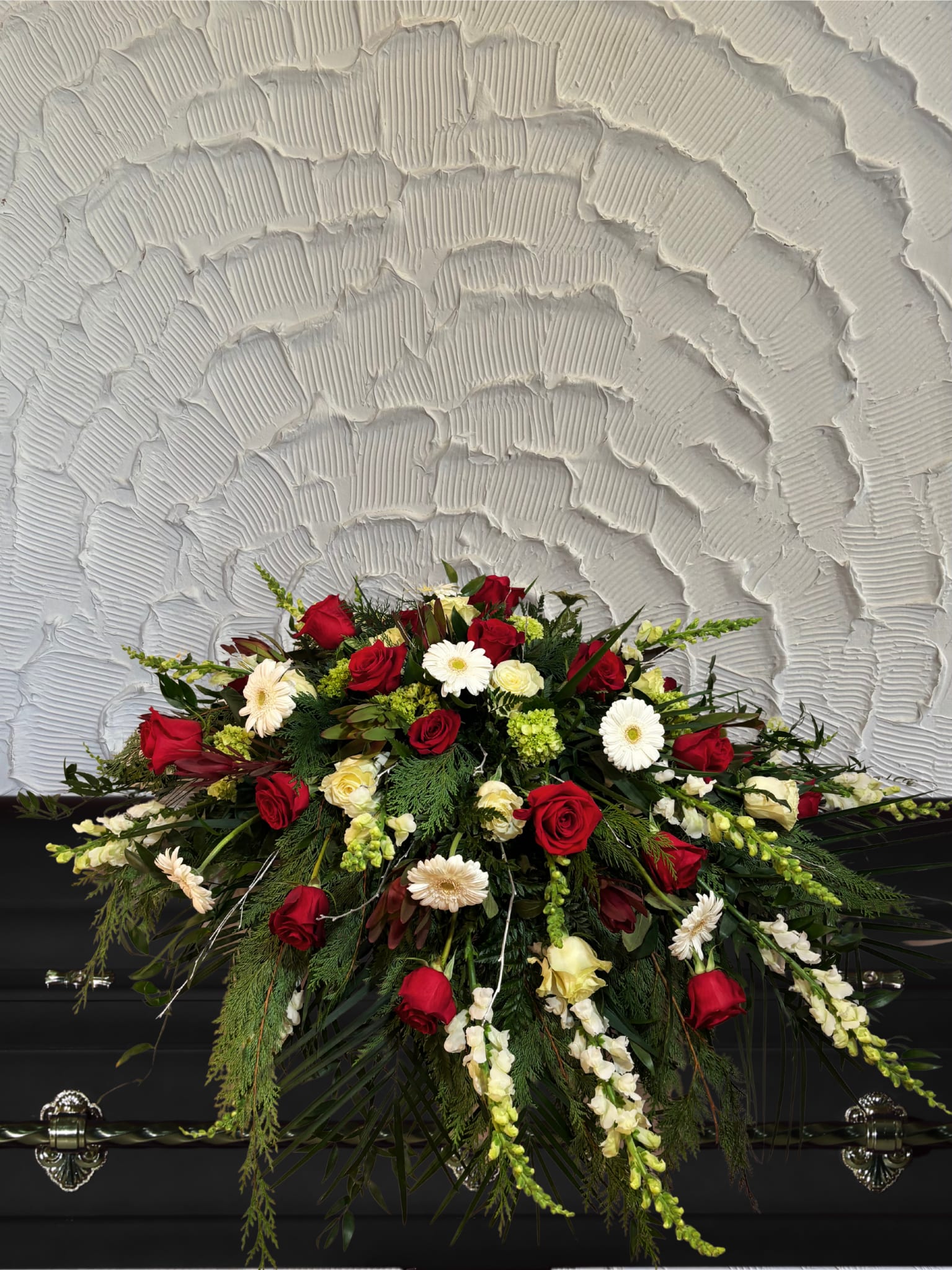 Red and white floral casket spray with roses and daisies