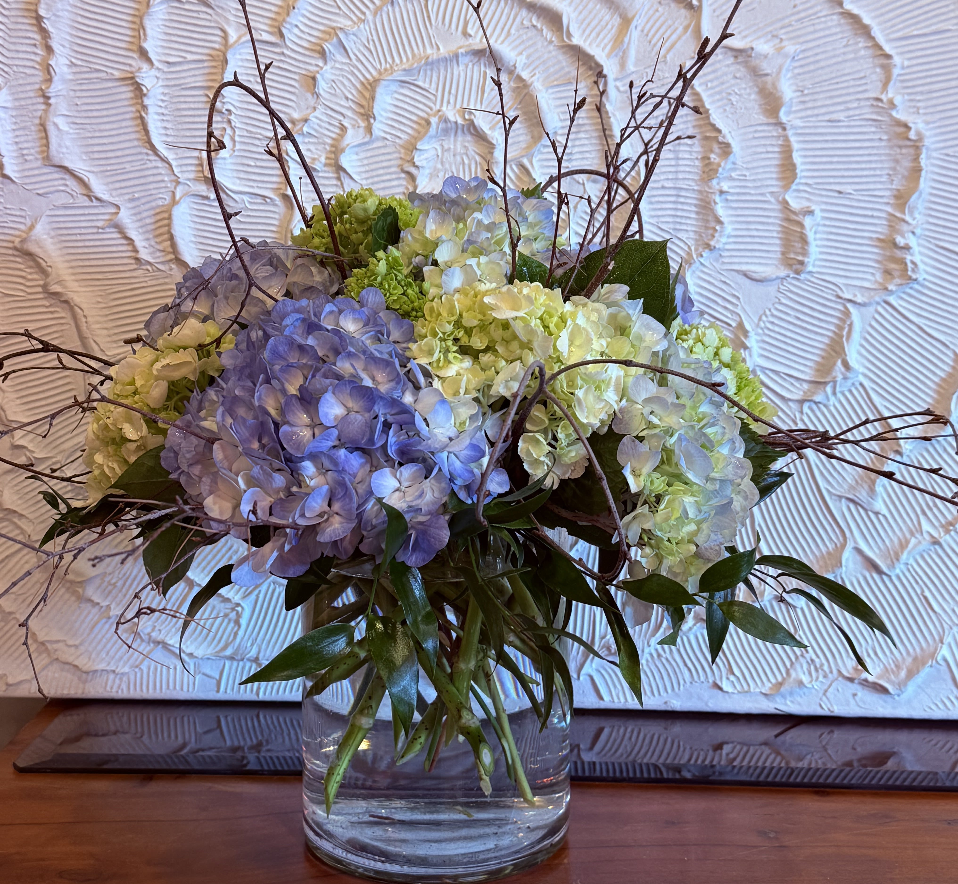 Blue and white hydrangea arrangement in a clear glass vase