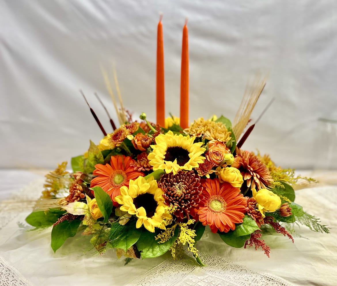 Harvest Traditions - This elegant table centerpiece is created using seasonal garden flowers including sunflowers and tapered candles. Harvest Traditions is the perfect hostess gift or for your own table.  This is just the right size for a table that seats 8-12 people. Pair this with our Pumpkin Spice Voluspa candle for the perfect finishing touch to your gift!  