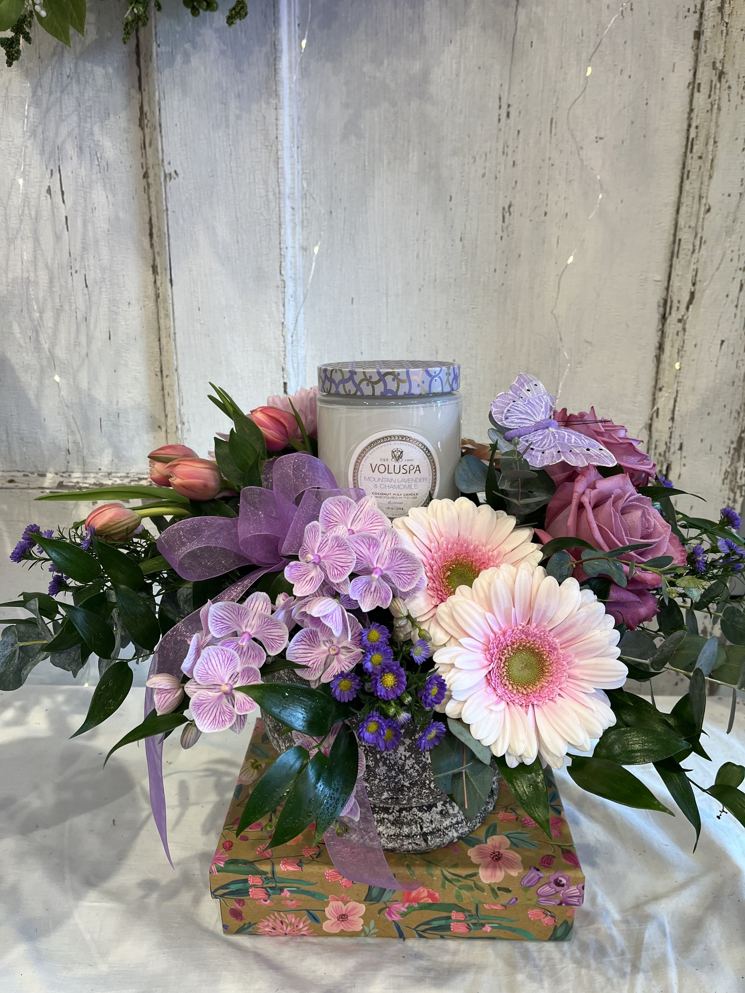 Summer Candlelight  - Stone Compote featuring an 18 ounce Mountain Lavender &amp; Chamomile Voluspa candle.  Selection of lavender &amp; pink seasonal garden flowers with accents of eucalyptus.