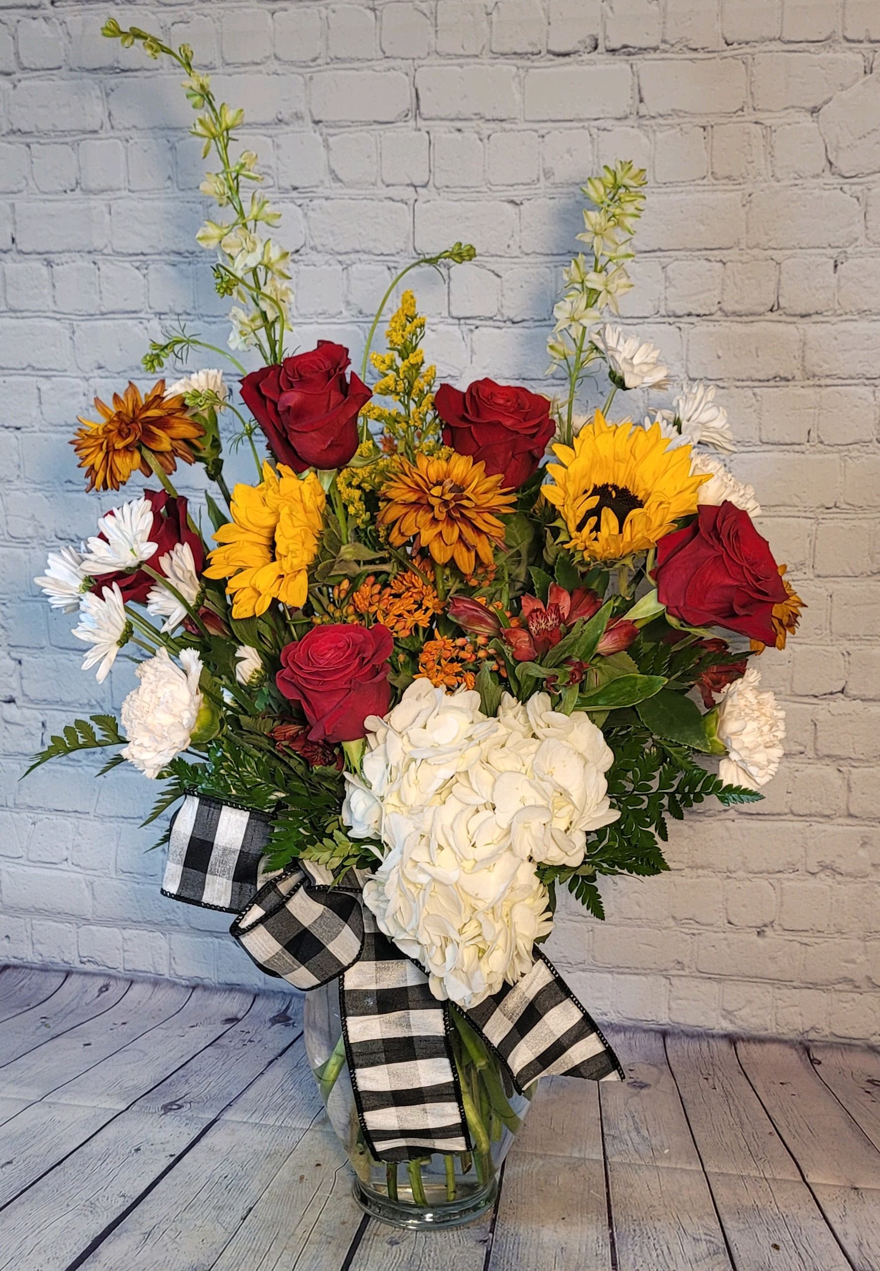 The Farmhouse Classic - A grand summery mix of sunflowers and red roses will be a delight for any recipient. This bouquet also includes hydrangea, Black Eyed Susans, solidago, and larkspur. 