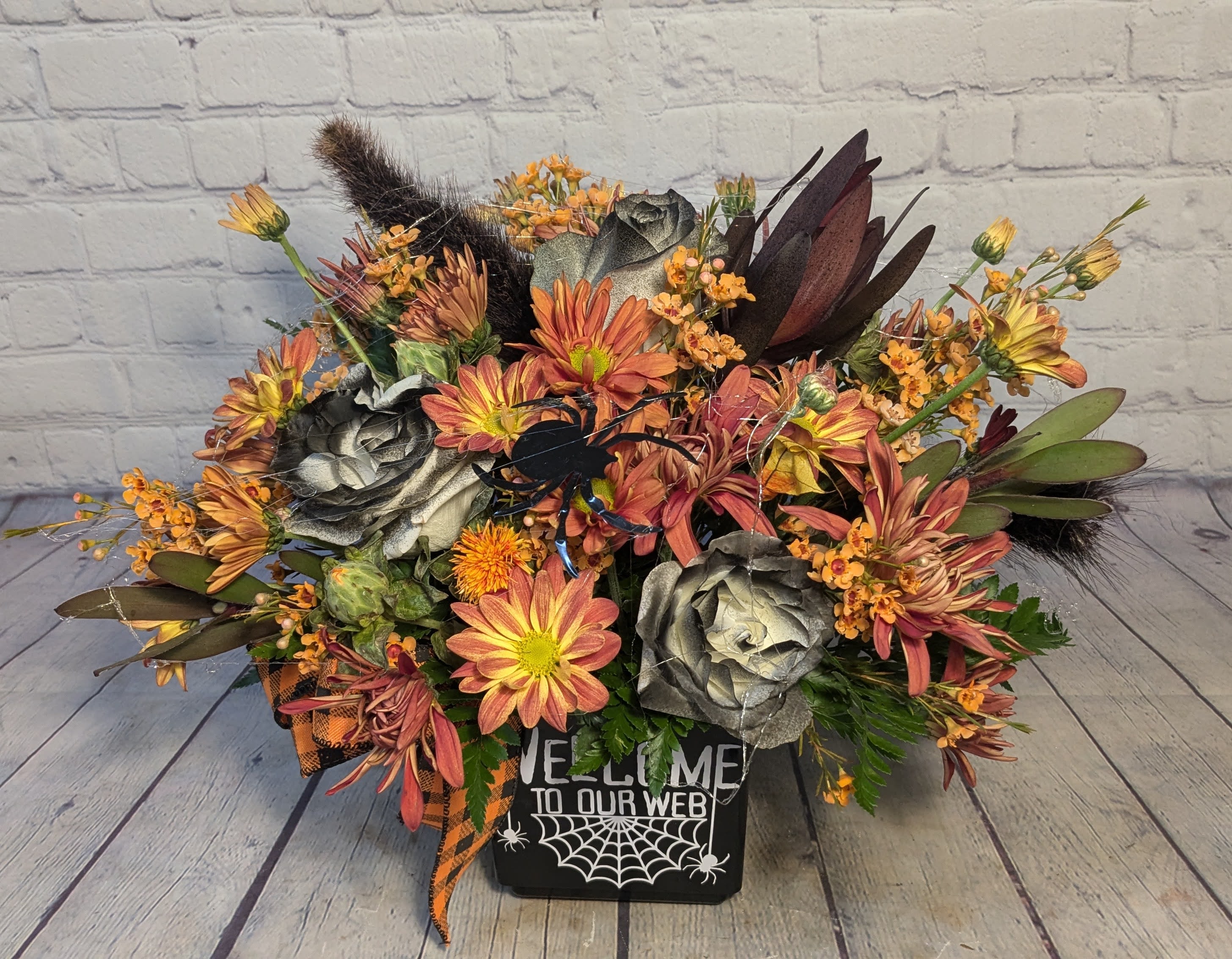 Welcome To Our Web - This bouquet is a little spooky but a lot of fun! With Saff Flower, tinted roses, millet plumes, Safari Sunset, wax flower, &amp; mixed daisies; this bouquet is sure to be a hit this season. 
