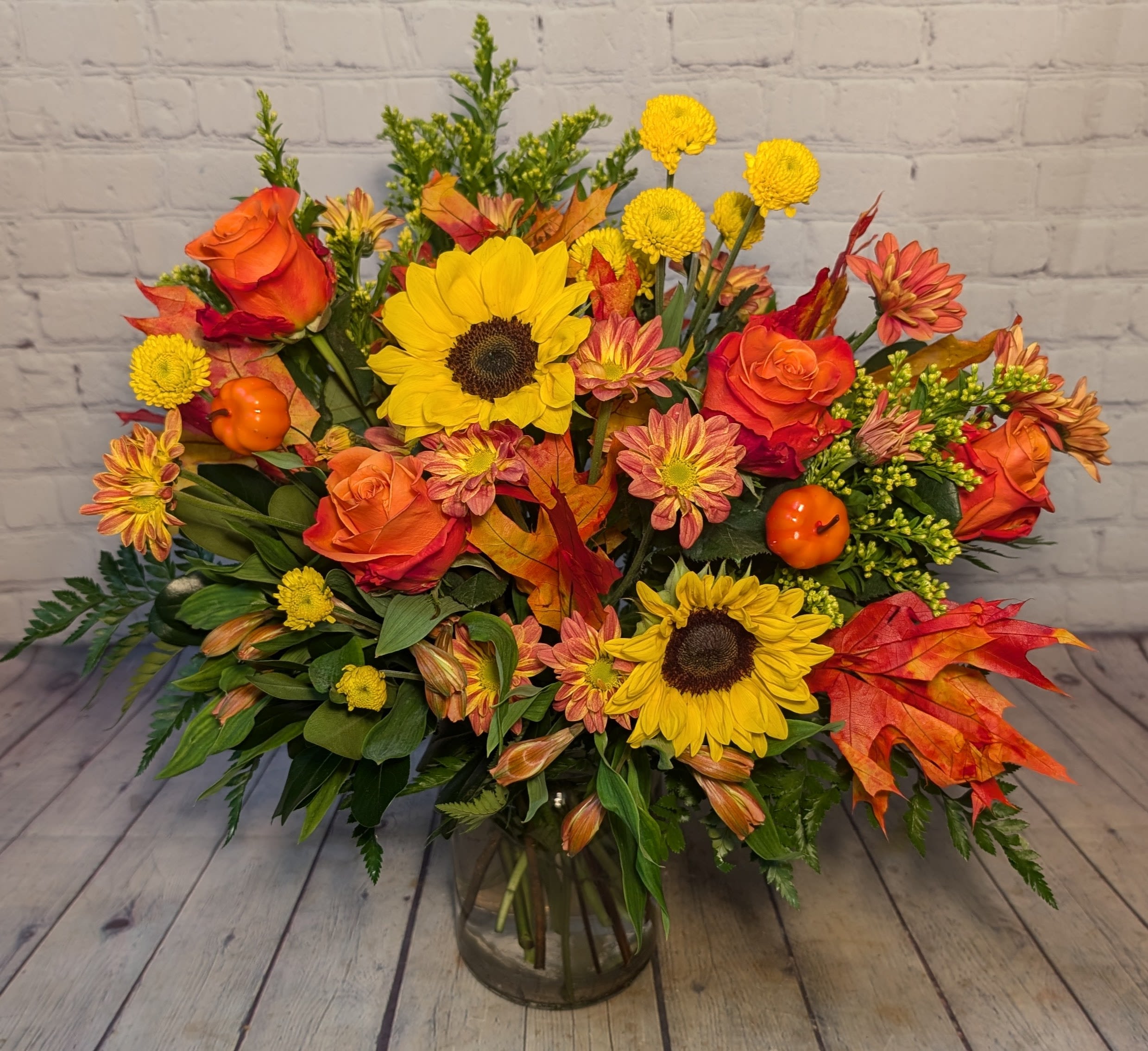 Harvest Glow - Bring the warmth of autumn indoors with our Harvest Glow Bouquet. Bursting with golden sunflowers, soft coral roses, cheerful mums, and seasonal accents of solidago and vibrant fall leaves, this design captures the cozy essence of fall. Playful mini pumpkins add a festive touch, making it the perfect centerpiece for your home, a thoughtful gift, or a way to brighten any space with seasonal cheer.