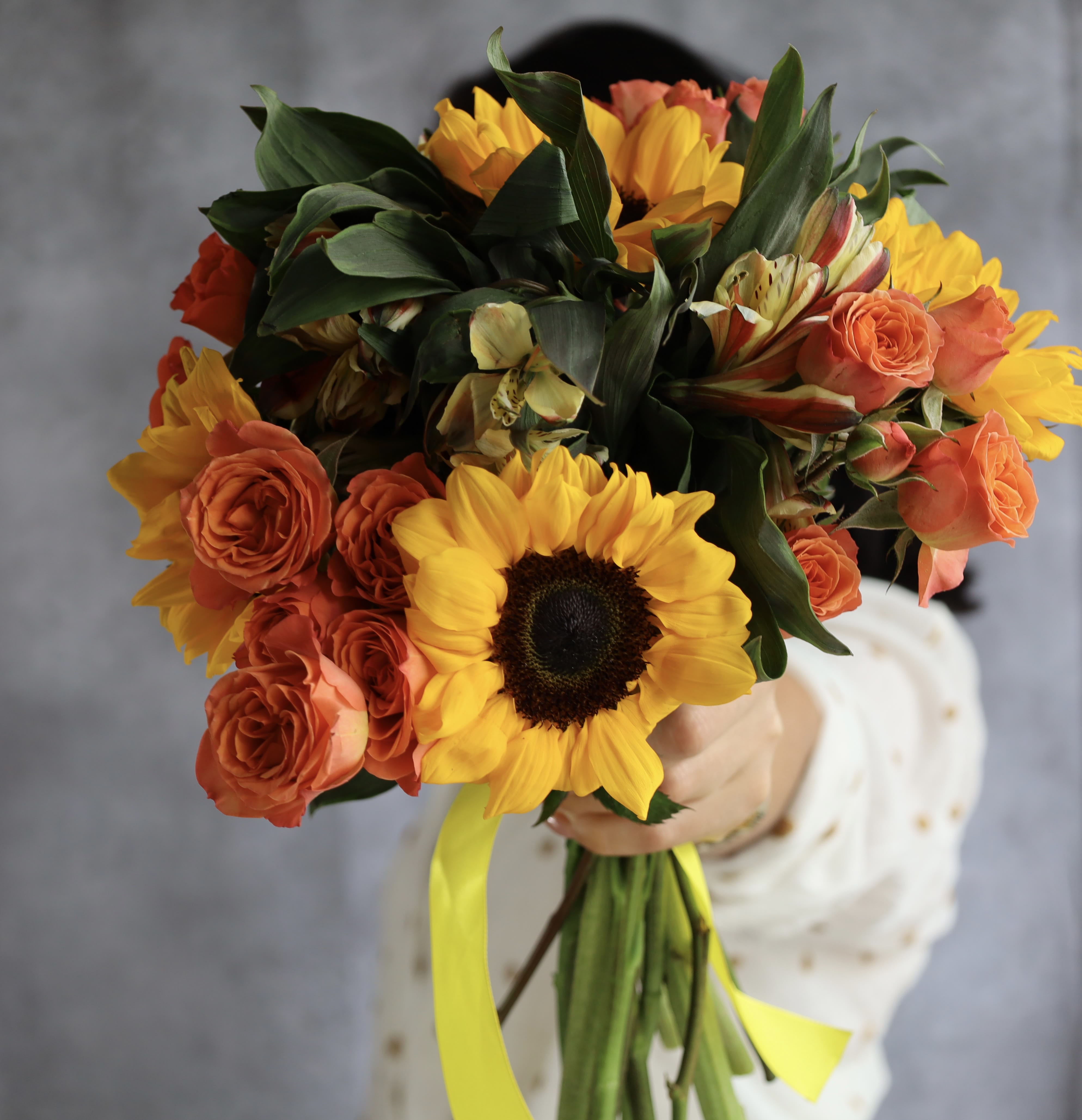 Bouquet of yellow sunflowers and orange roses tied with a yellow ribbon