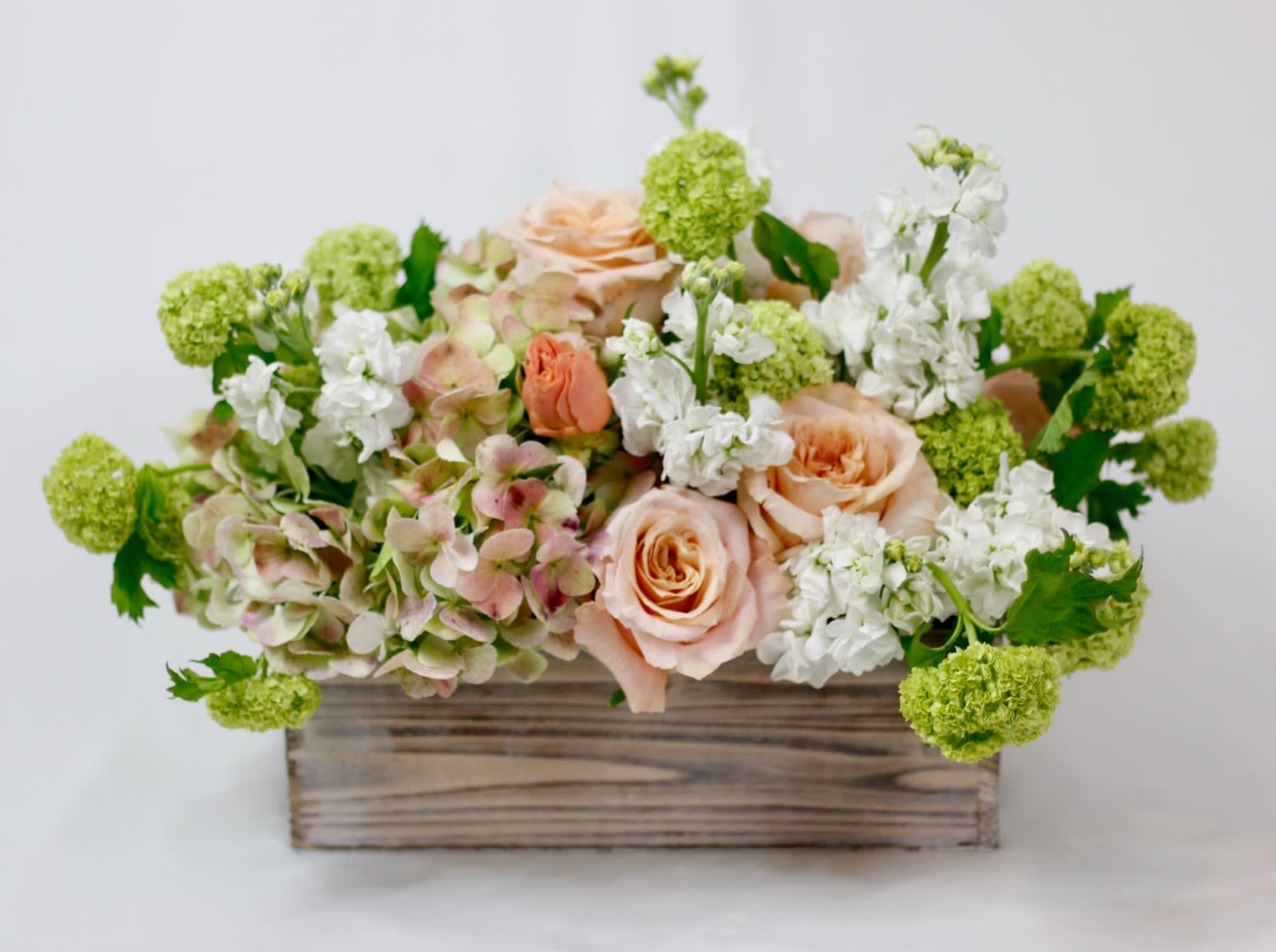 Peach roses and white flowers in a wooden box