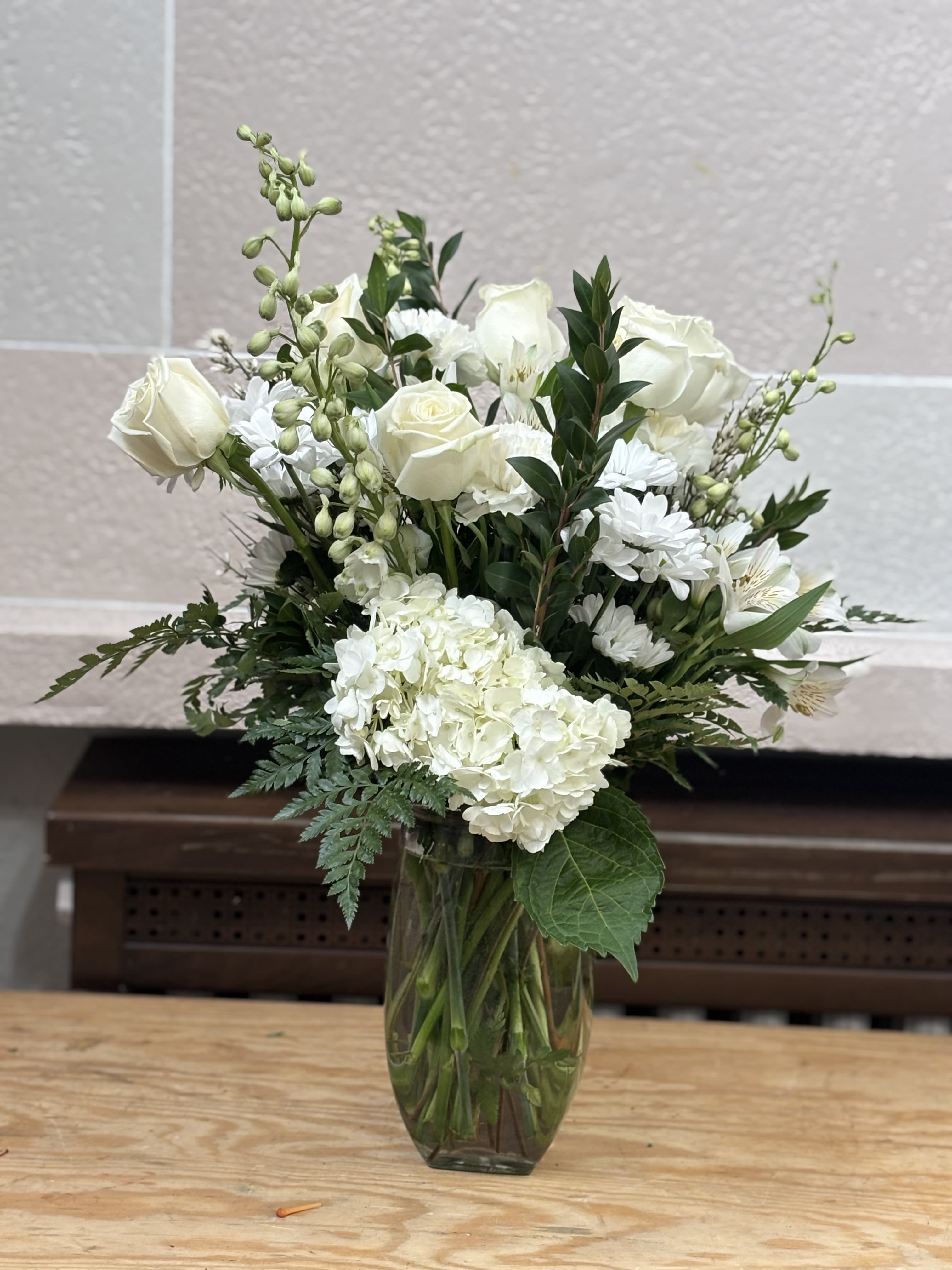White roses and hydrangeas in a clear glass vase