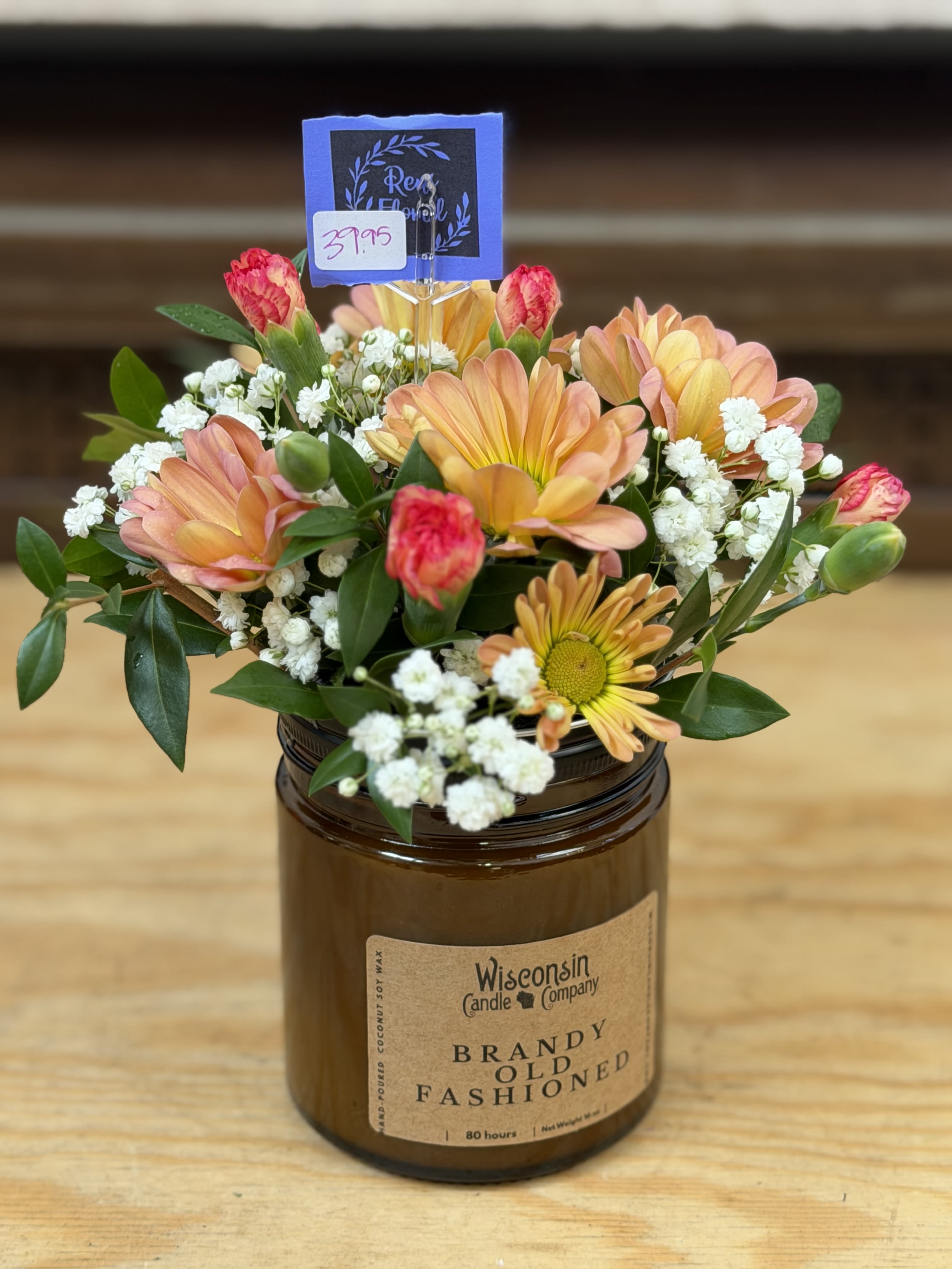 Candle Flower Arrangement - A 16 oz candle with a lid filled with fresh, bright flowers. *Colors may vary  Candle Scents Include:  Wisconsin Lilac-SOLD OUT Brandy Old Fashioned Lily of the Valley-SOLD OUT Lavender   **Please specify in special instructions which scent you would prefer**