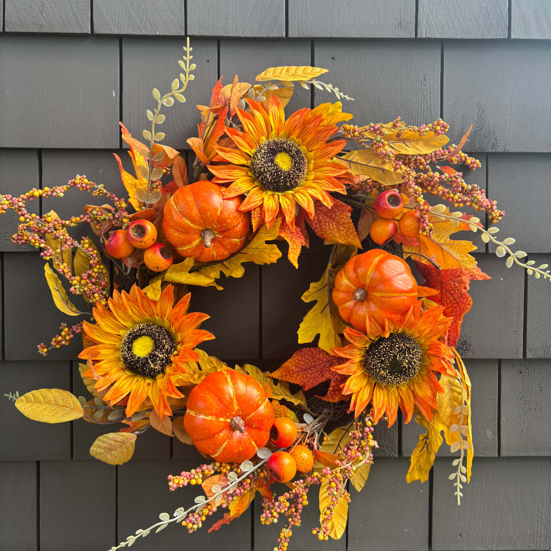 Autumn wreath with sunflowers, pumpkins, and berries on a dark wall