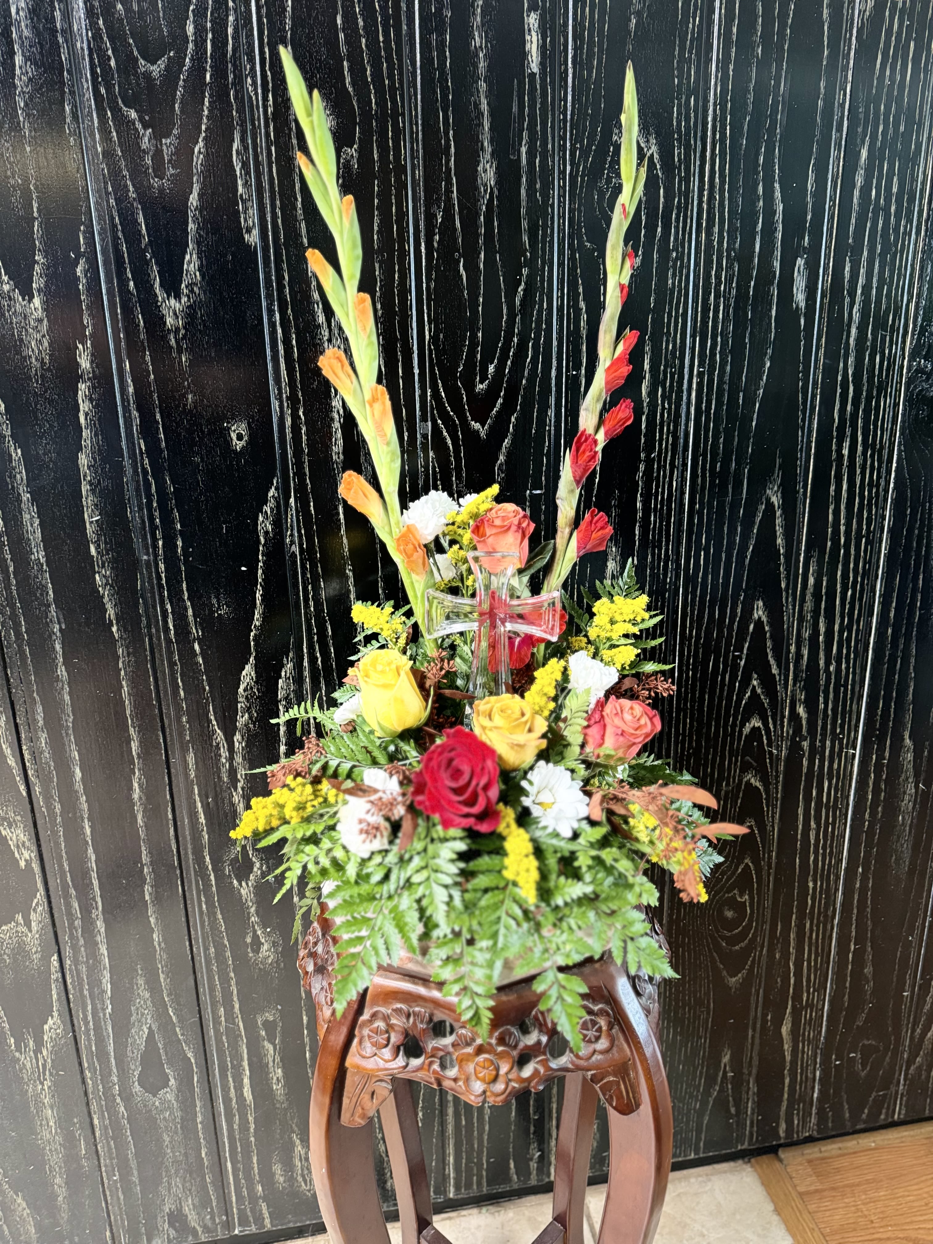 Tall floral arrangement with roses and gladiolus in a clear vase
