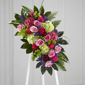 Standing floral spray with pink roses, hydrangeas, and carnations on a white easel