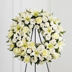White floral wreath on a black easel stand