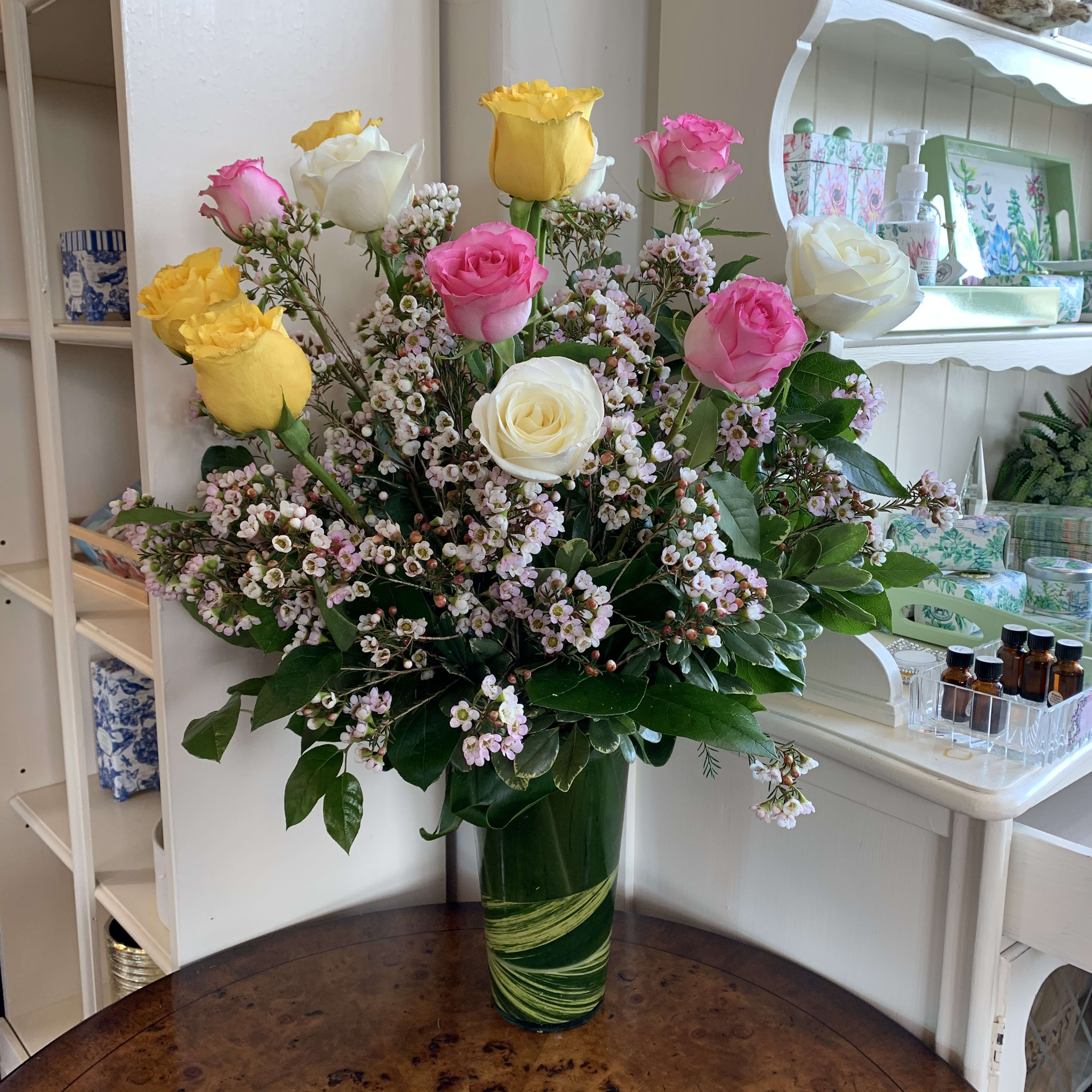 Bouquet of pink, yellow, and white roses in a green glass vase