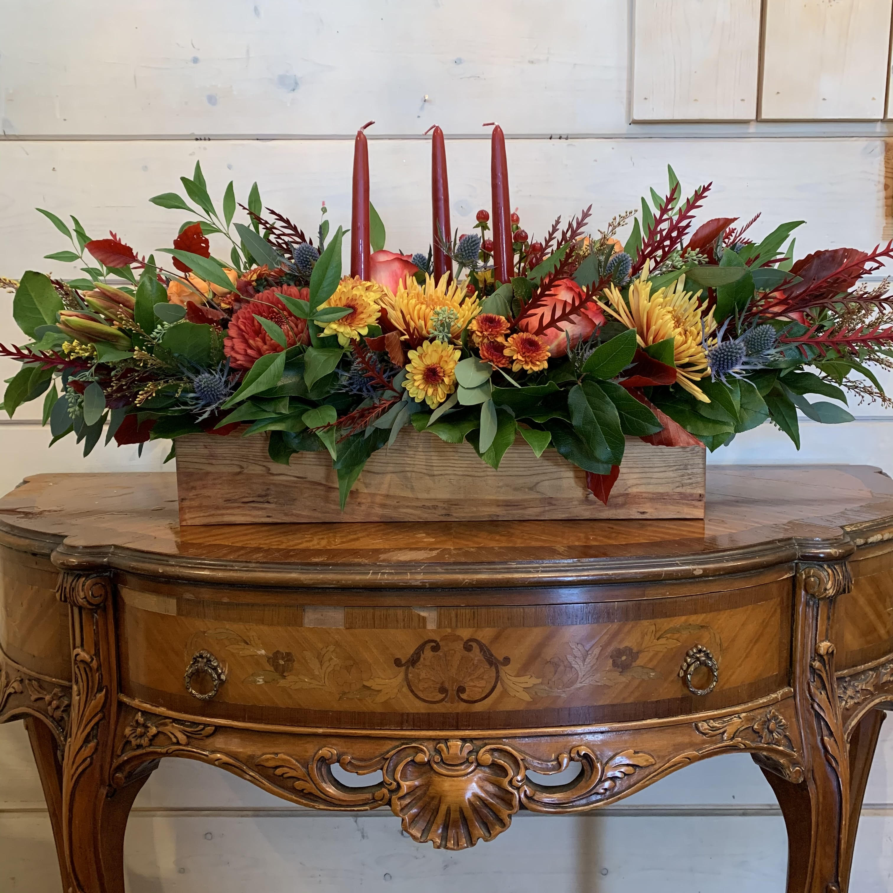 Long floral centerpiece with red candles in a wooden box