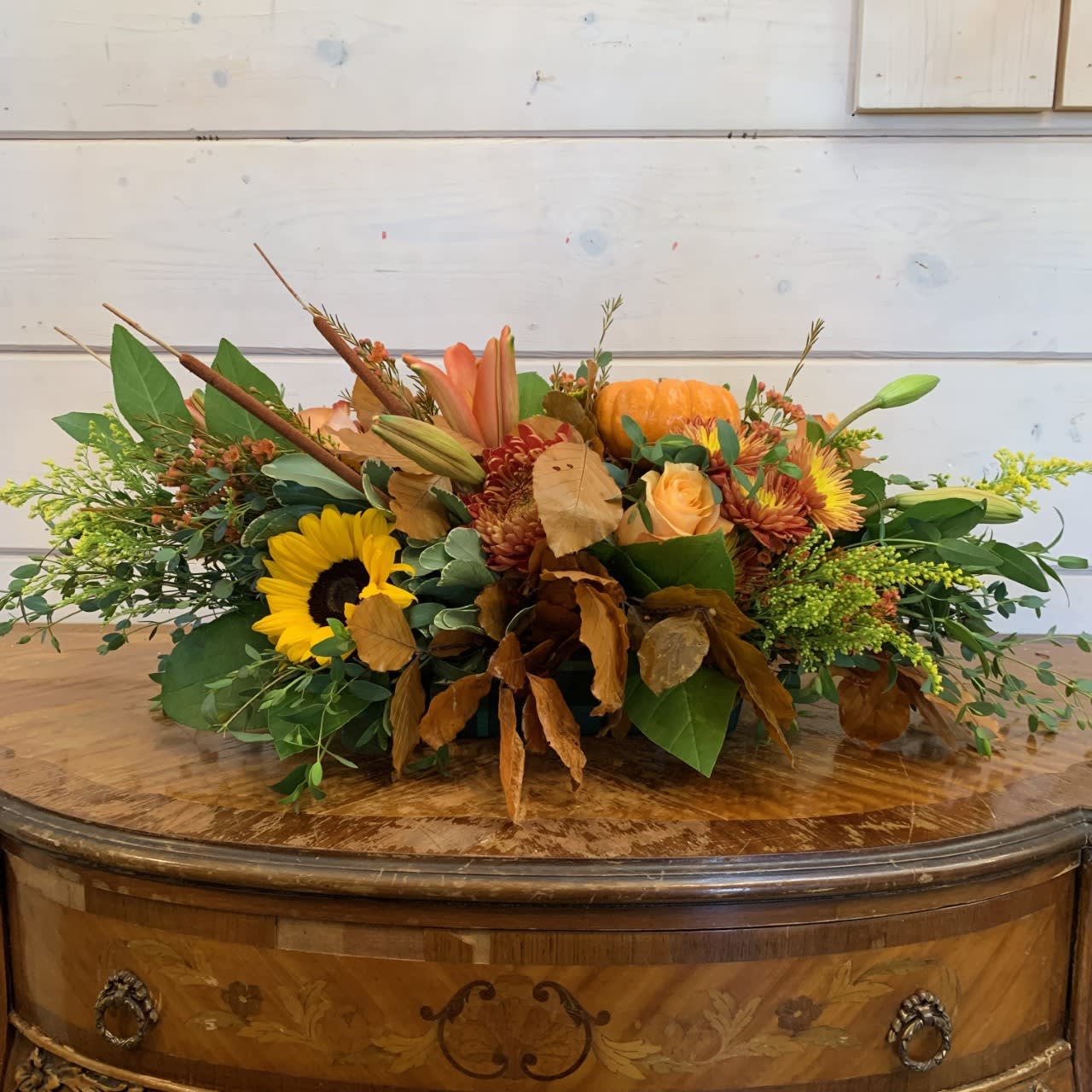 Autumn floral arrangement with sunflowers, roses, and a small pumpkin
