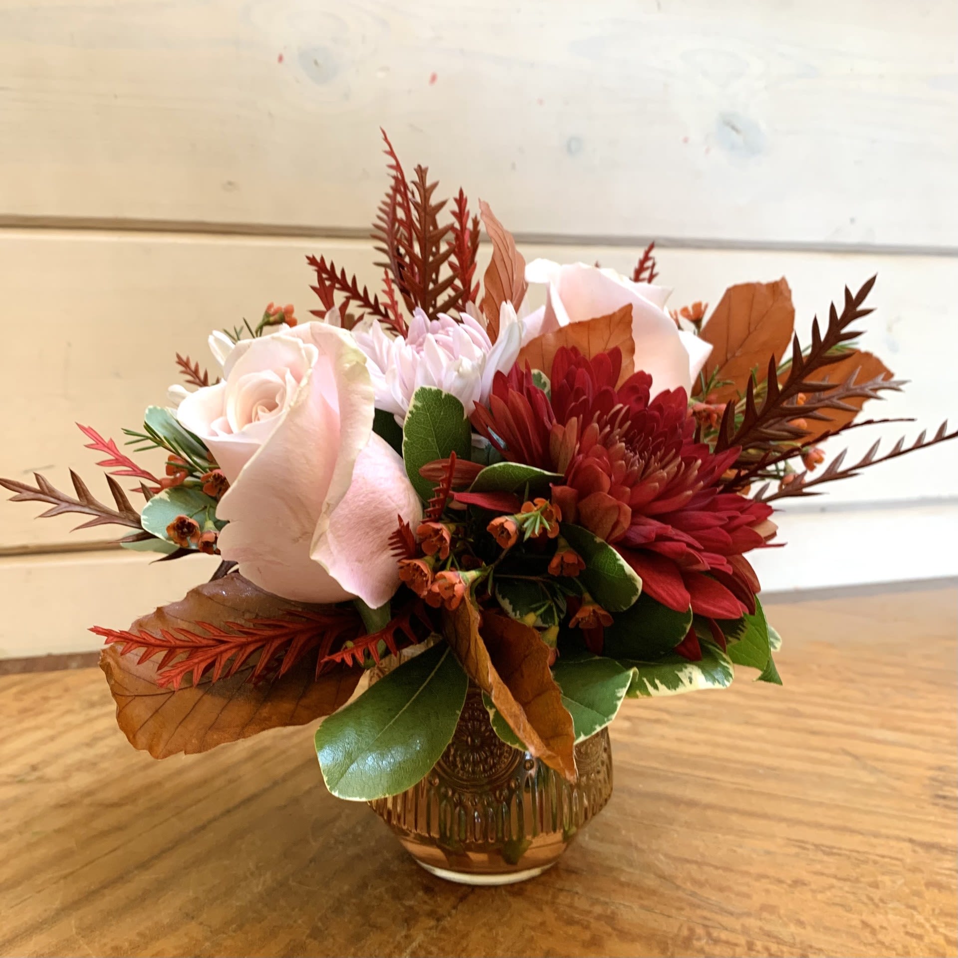 Pink roses and red mums arranged in a small glass vase