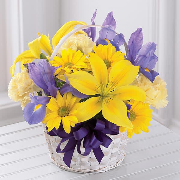 Yellow and purple mixed bouquet in a white basket with a ribbon