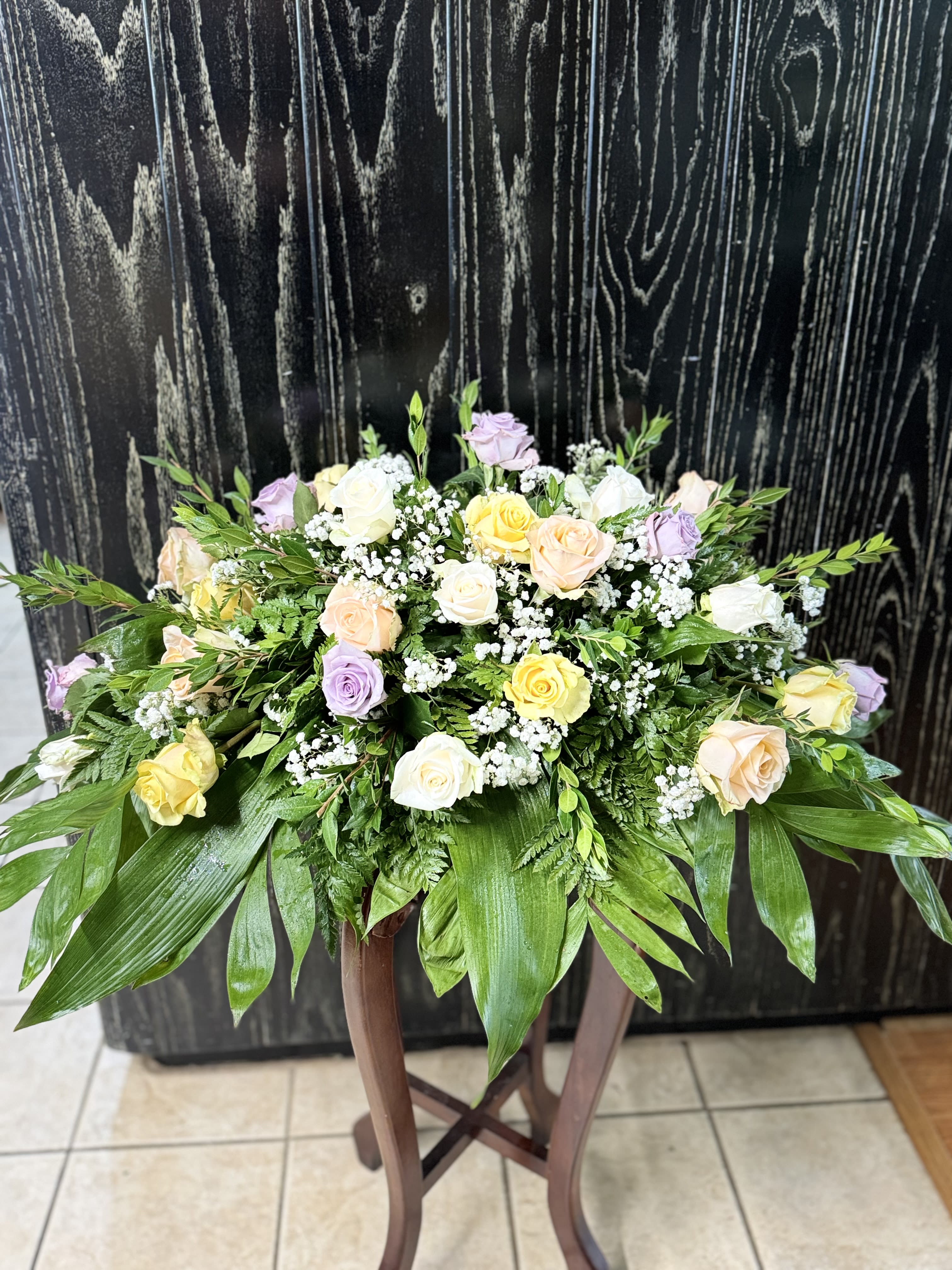 Pastel roses and baby's breath in a low arrangement on a stand