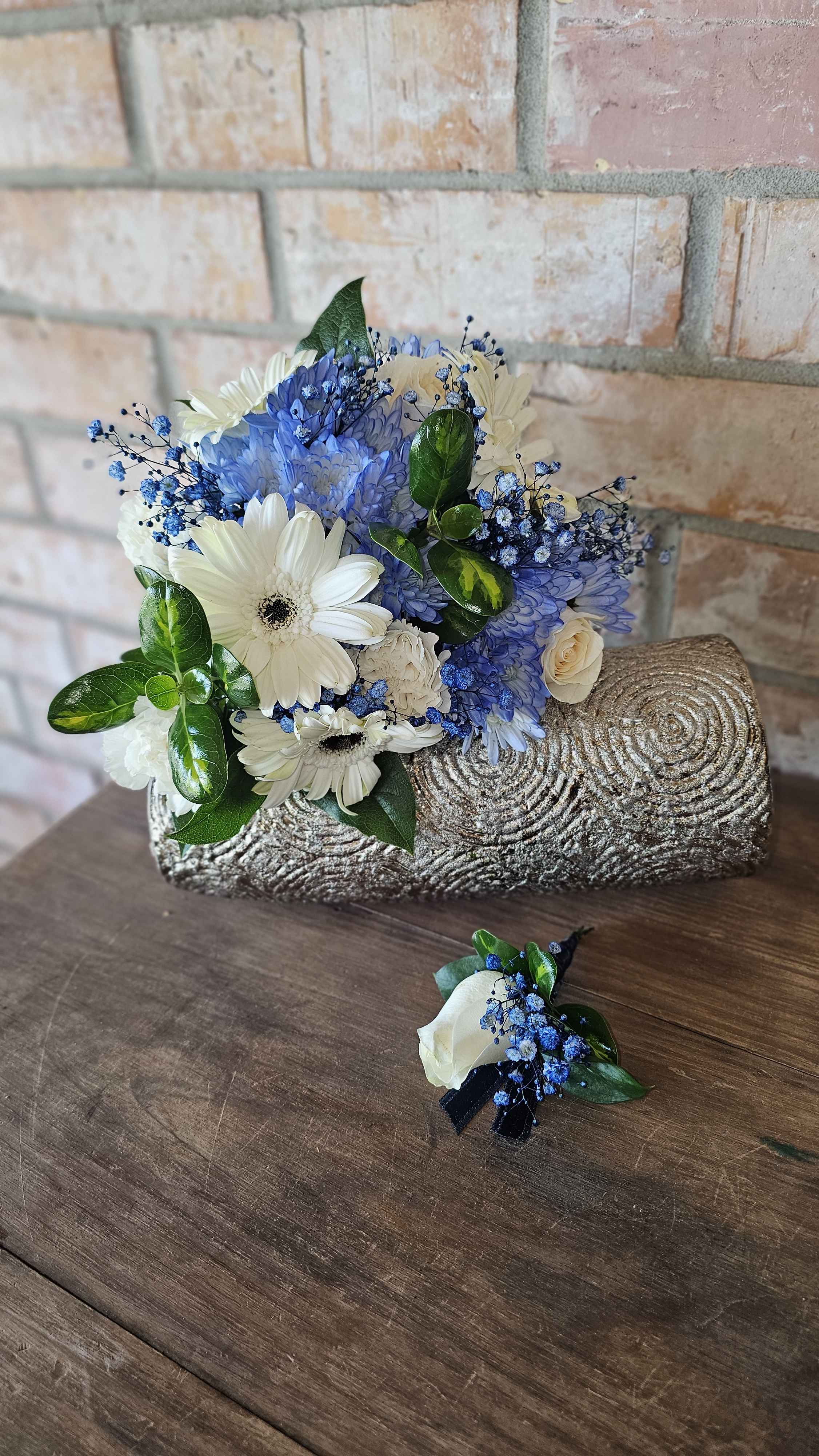 Blue and white bouquet with daisies and roses in a textured silver clutch