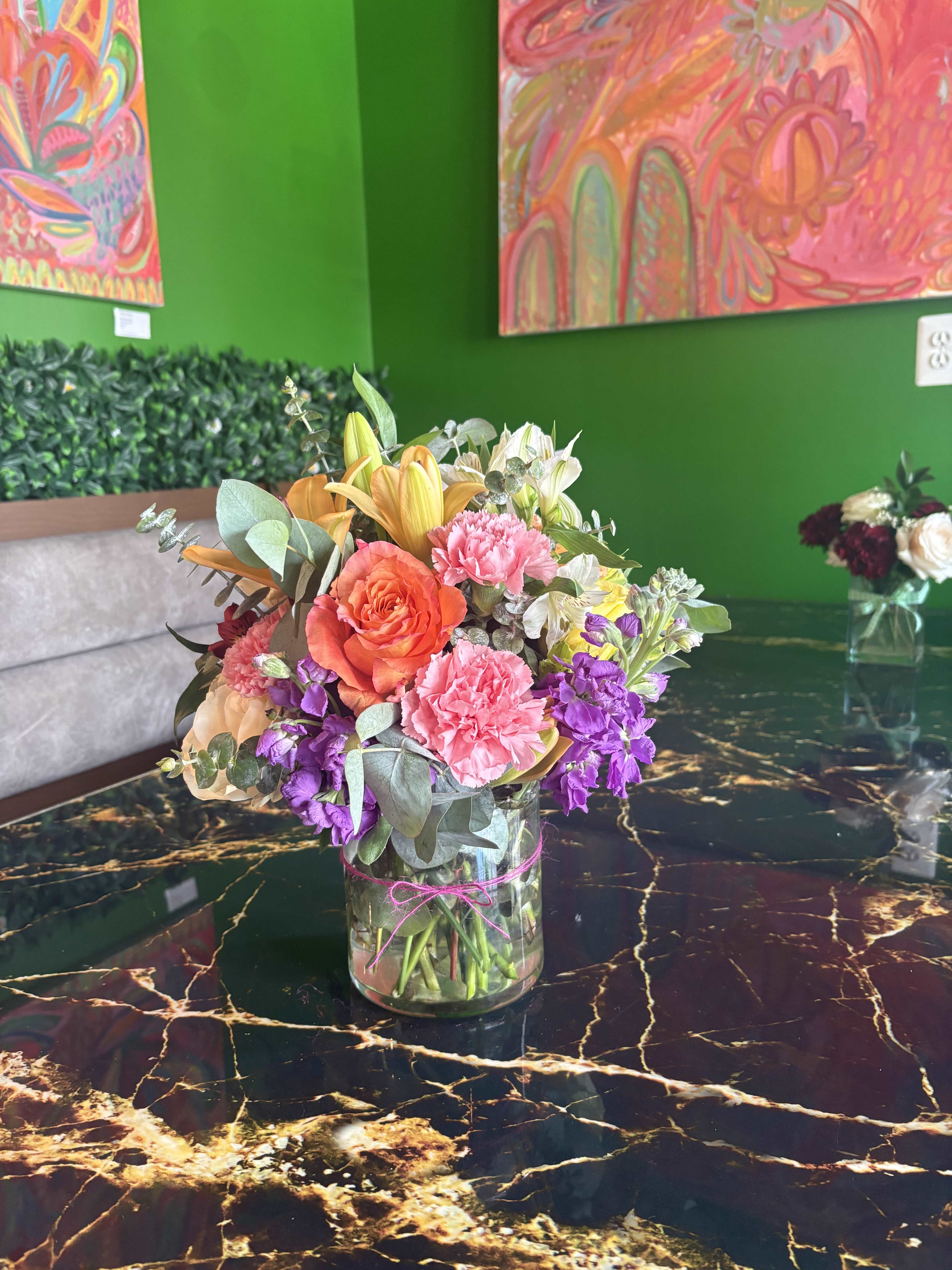 Mixed bouquet in a clear glass vase with pink, orange, purple, and white flowers