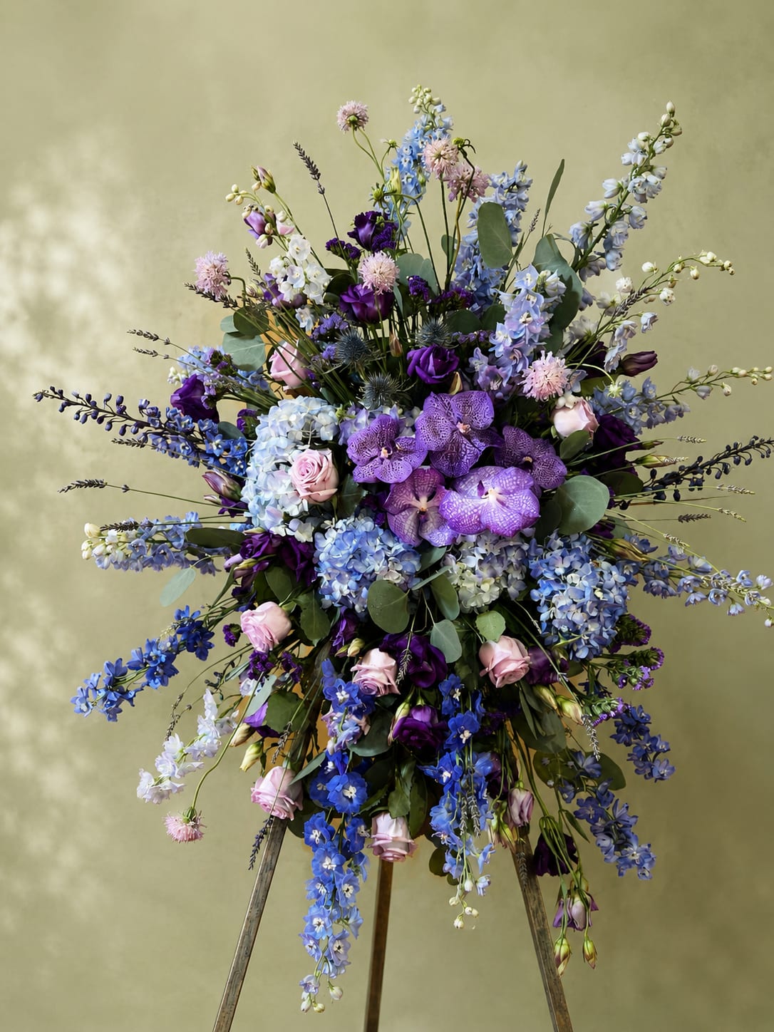 Lavender Skies Sympathy Spray - “A graceful standing spray showcasing lavender orchids, hydrangeas, delphiniums, and soft pink roses. Designed with elegance and serenity, this tribute offers a beautiful expression of remembrance, comfort, and heartfelt sympathy.”