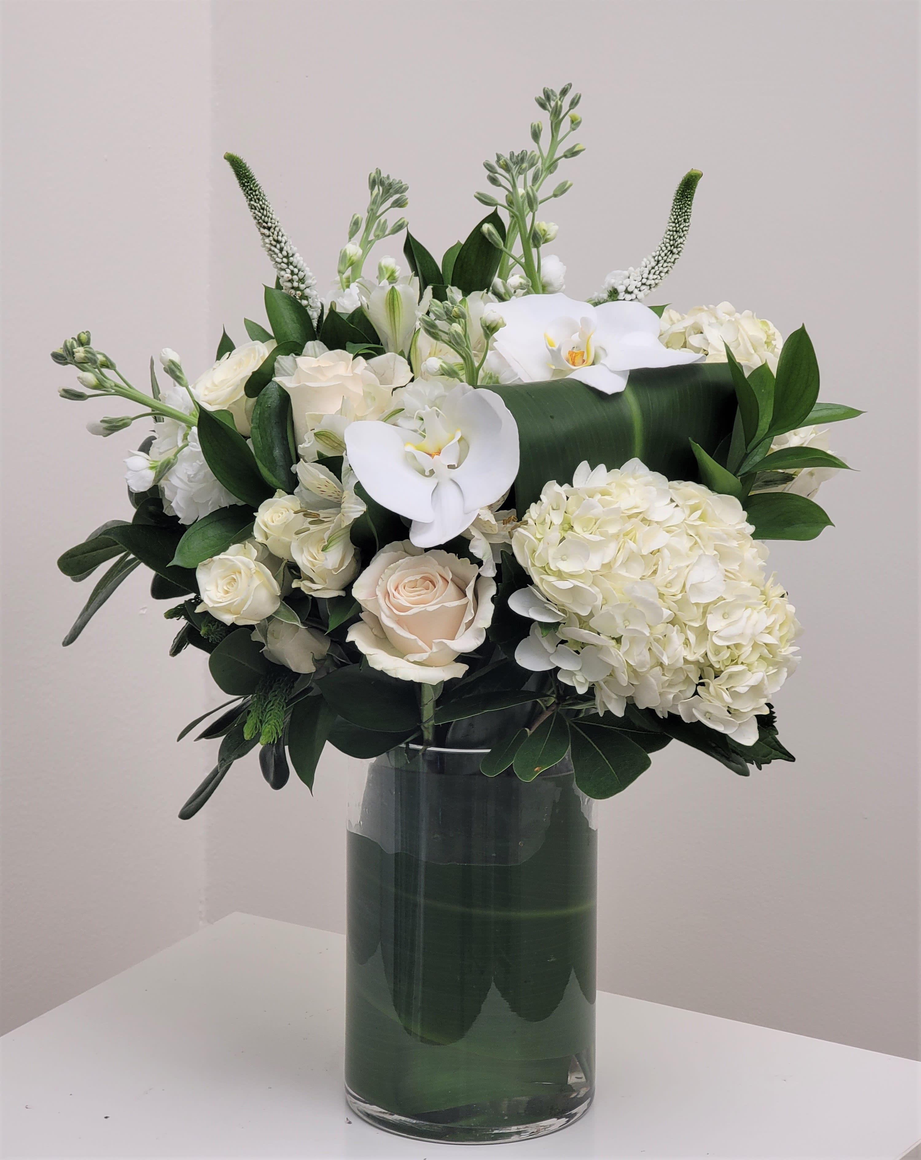 Guiding Grace Bouquet - Share comfort, love, and solace with a bouquet designed with pure white blooms. An array of hydrangea, stock, roses, and lisianthus combine in a glass vase to create our Guiding Grace Bouquet. While this arrangement is simply immense, it is best placed on a large table or within the home of your loved ones. Approximately 24" H x 18" W.  
