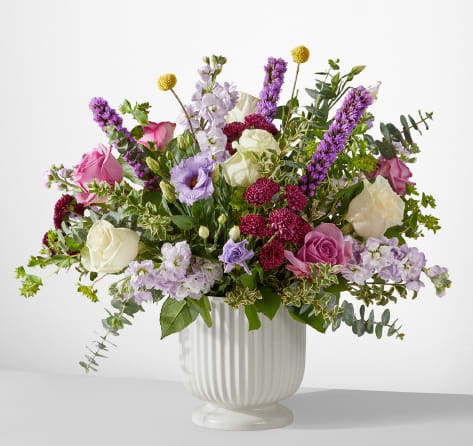 Mixed bouquet of pink, white, and lavender flowers in a white vase