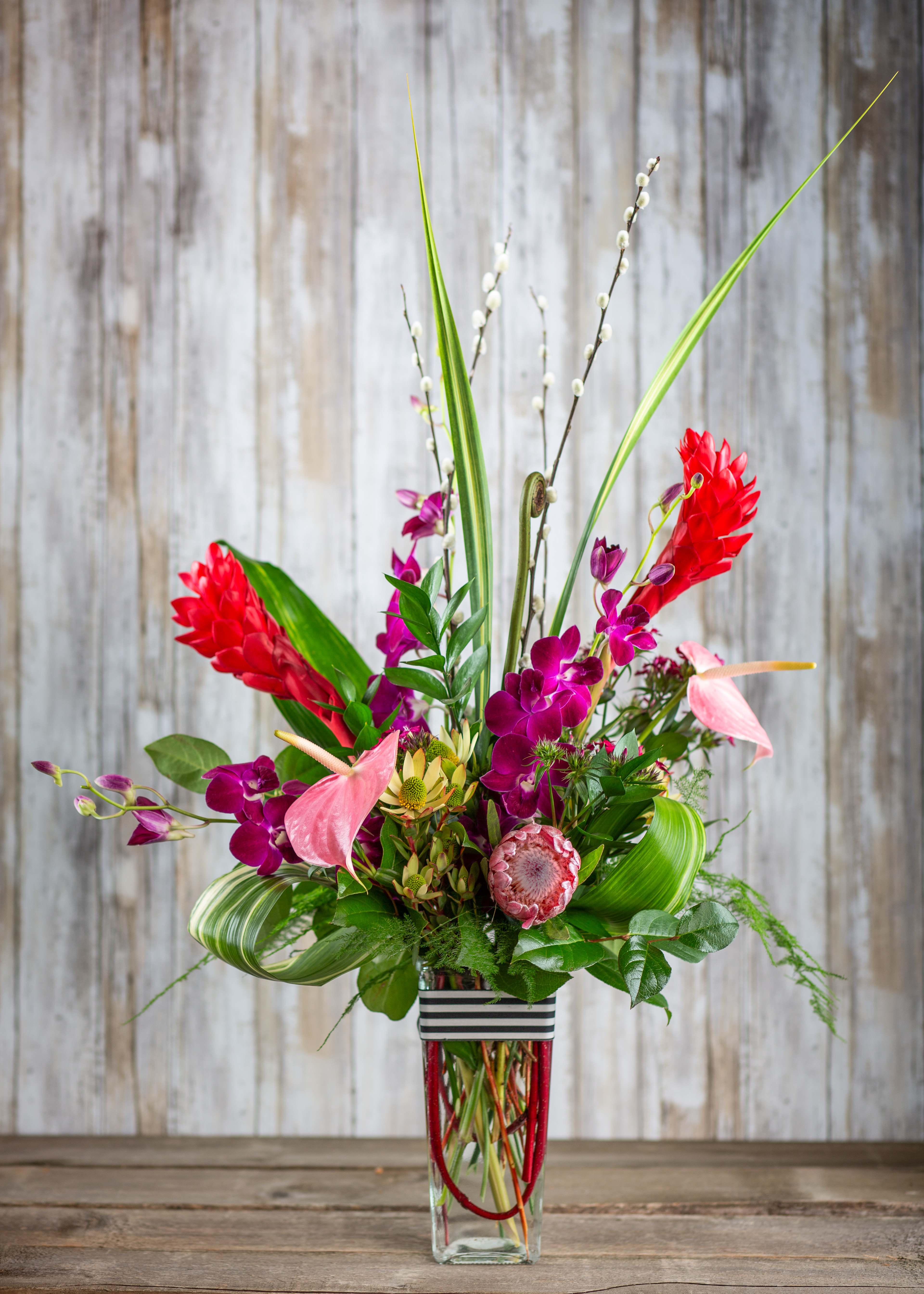 Tropical bouquet with pink orchids and red ginger in a glass vase