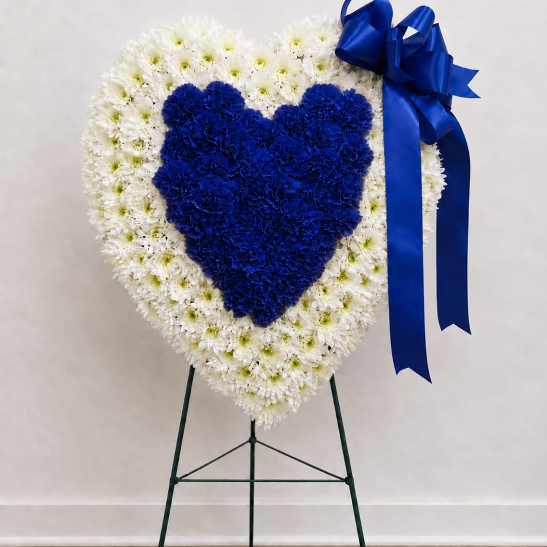 Heart-shaped white and blue floral standing spray on an easel with ribbon