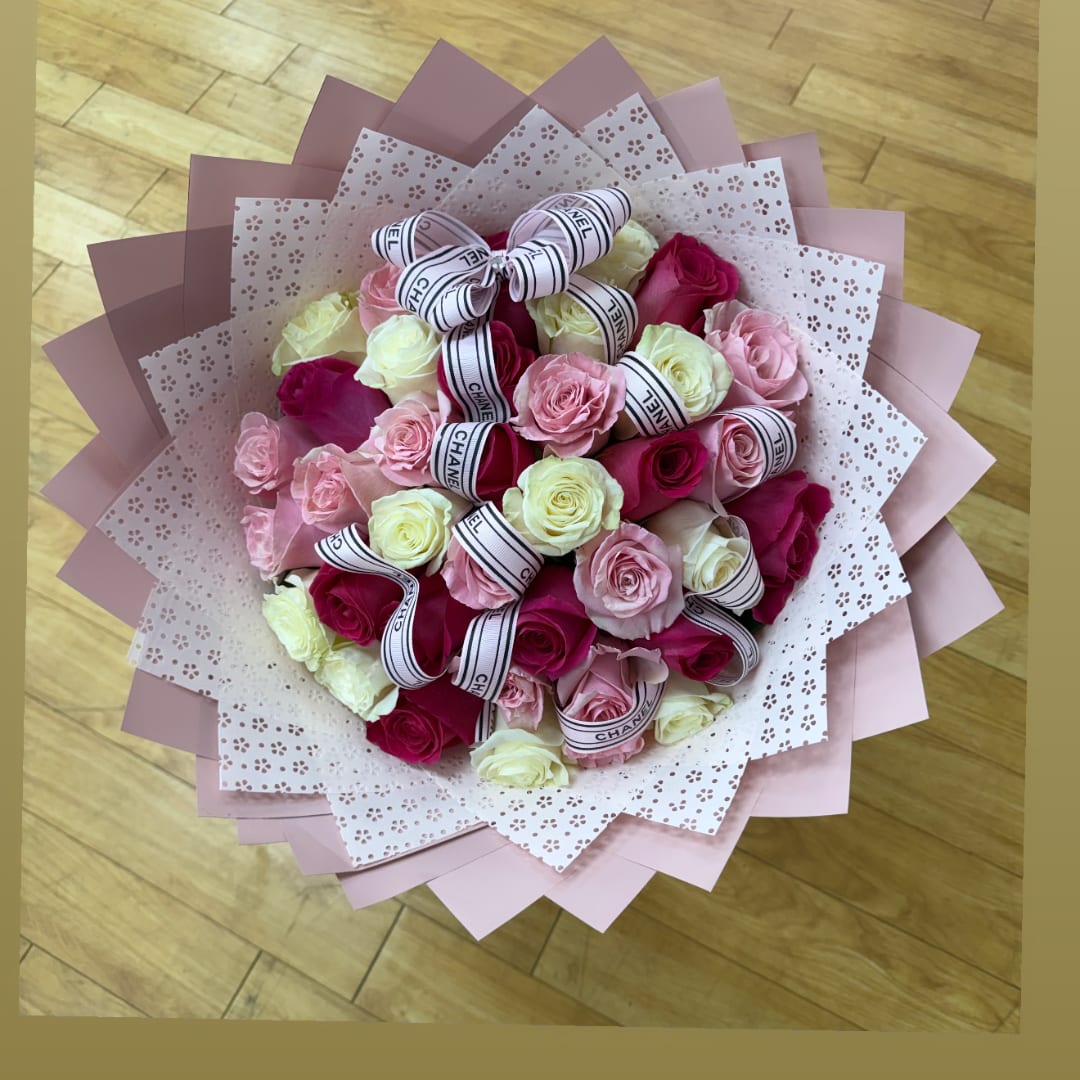Bouquet of pink and cream roses wrapped in patterned paper