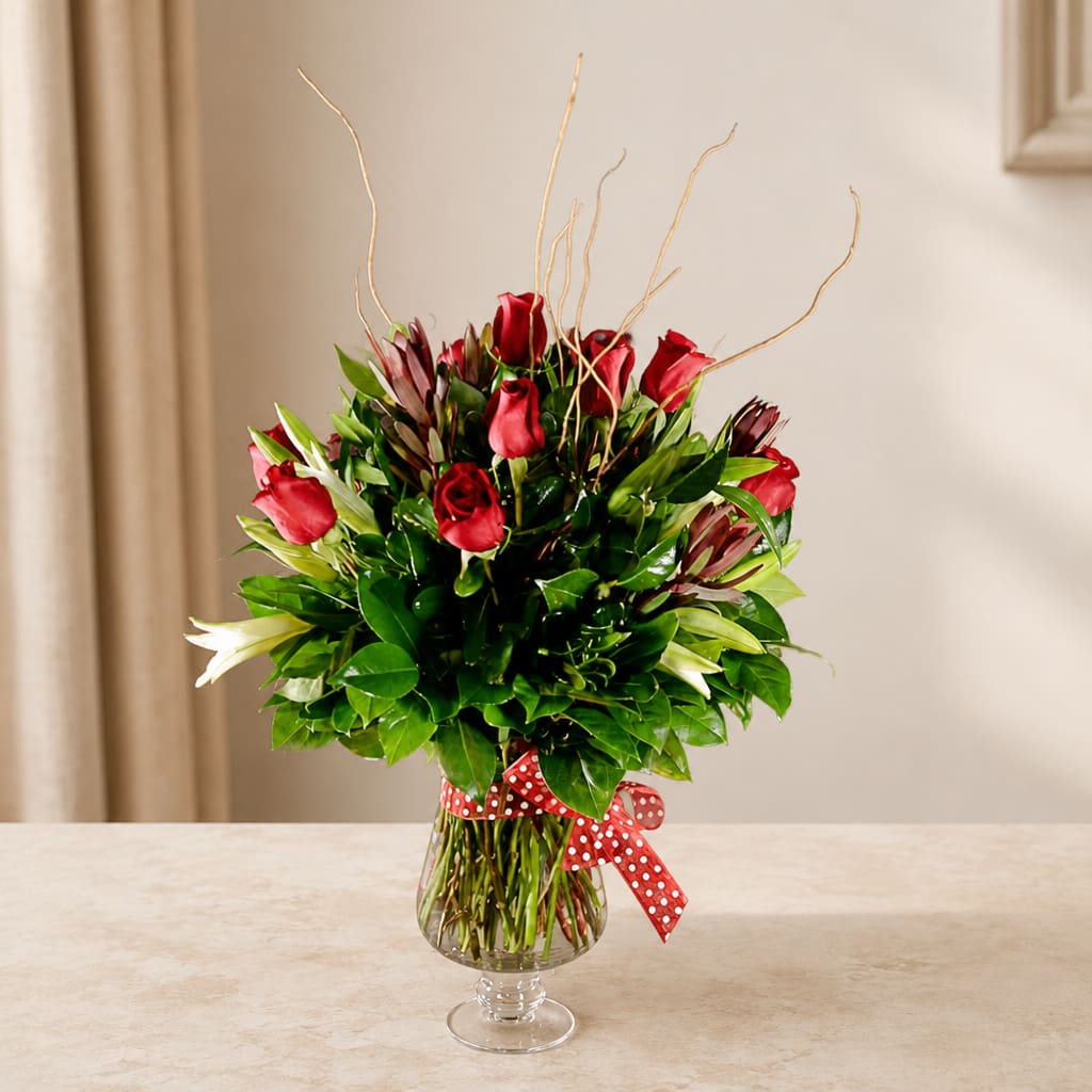 Red roses in a clear glass vase with a red polka-dot ribbon