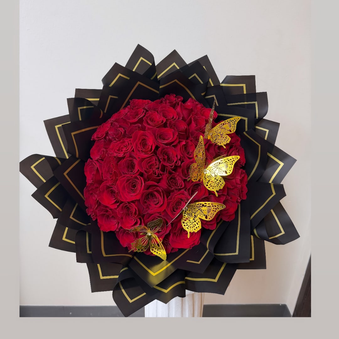 Large bouquet of red roses wrapped in black paper with gold trim and butterfly accents