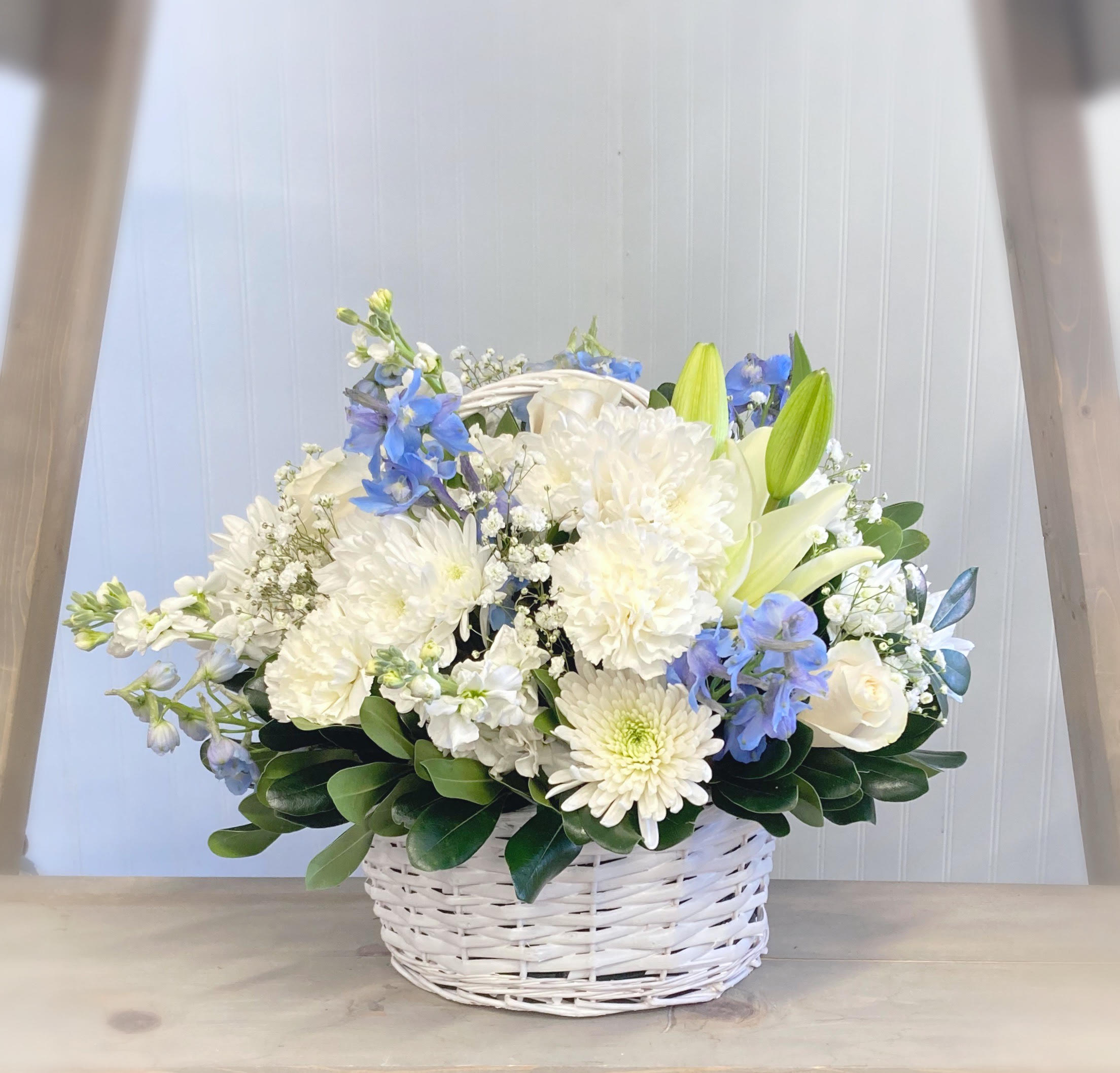 White and blue flower arrangement in a white wicker basket