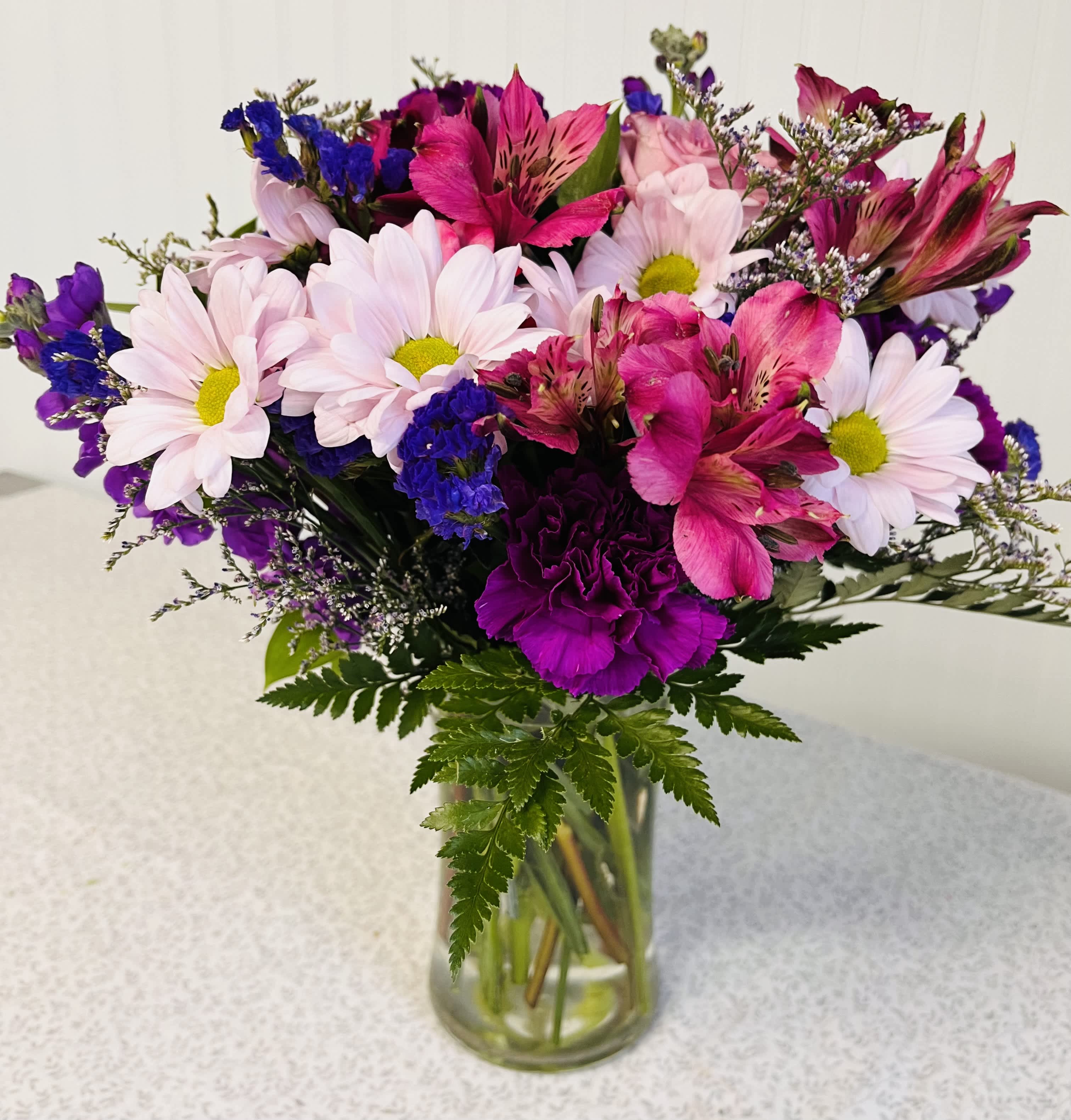 Bouquet of pink daisies and magenta alstroemeria in a glass vase