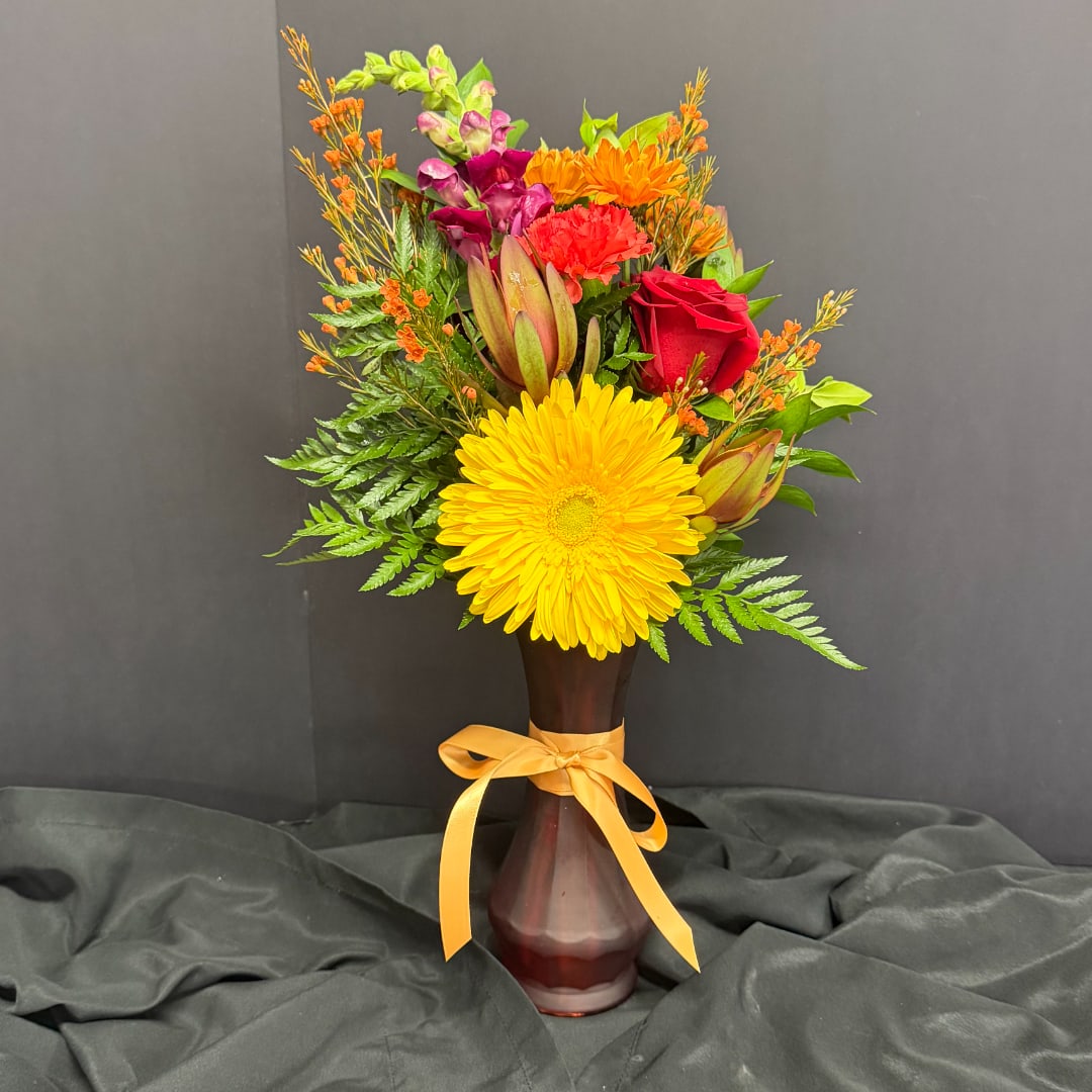 Mixed bouquet with yellow gerbera, red rose, and orange flowers in a vase
