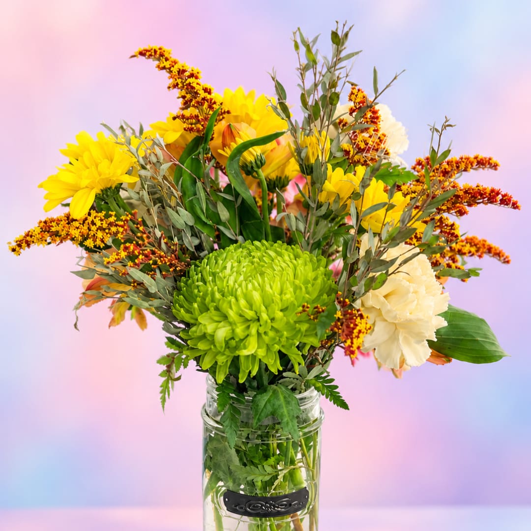 Yellow and cream flower arrangement in a clear glass jar vase