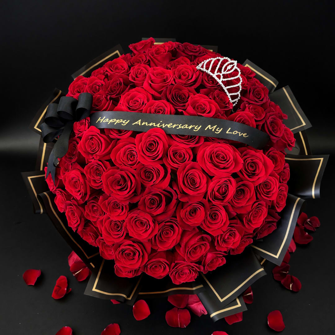 Heart-shaped bouquet of red roses with a black anniversary ribbon and tiara
