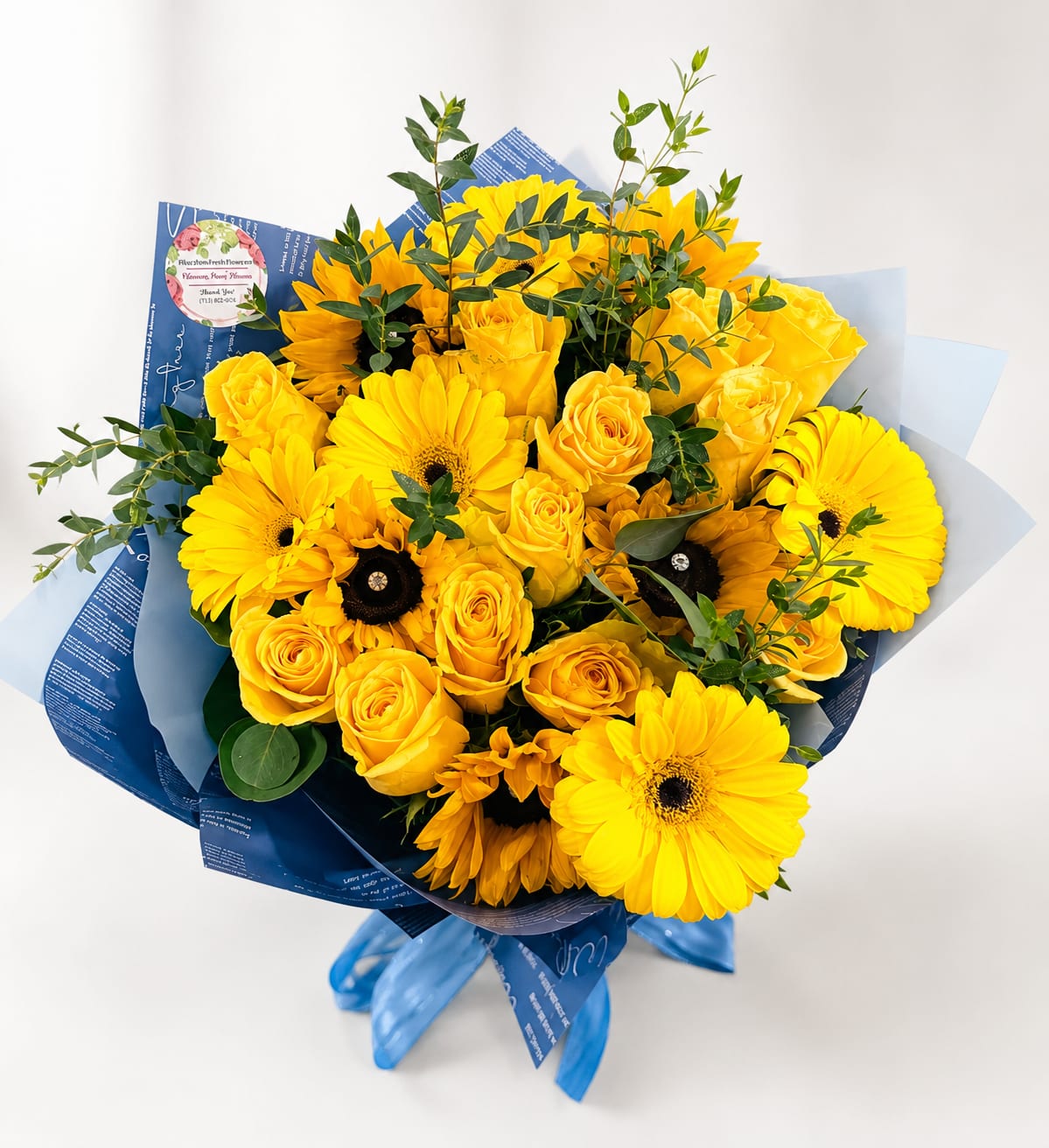 Yellow roses and gerbera daisies in blue wrapping with ribbon