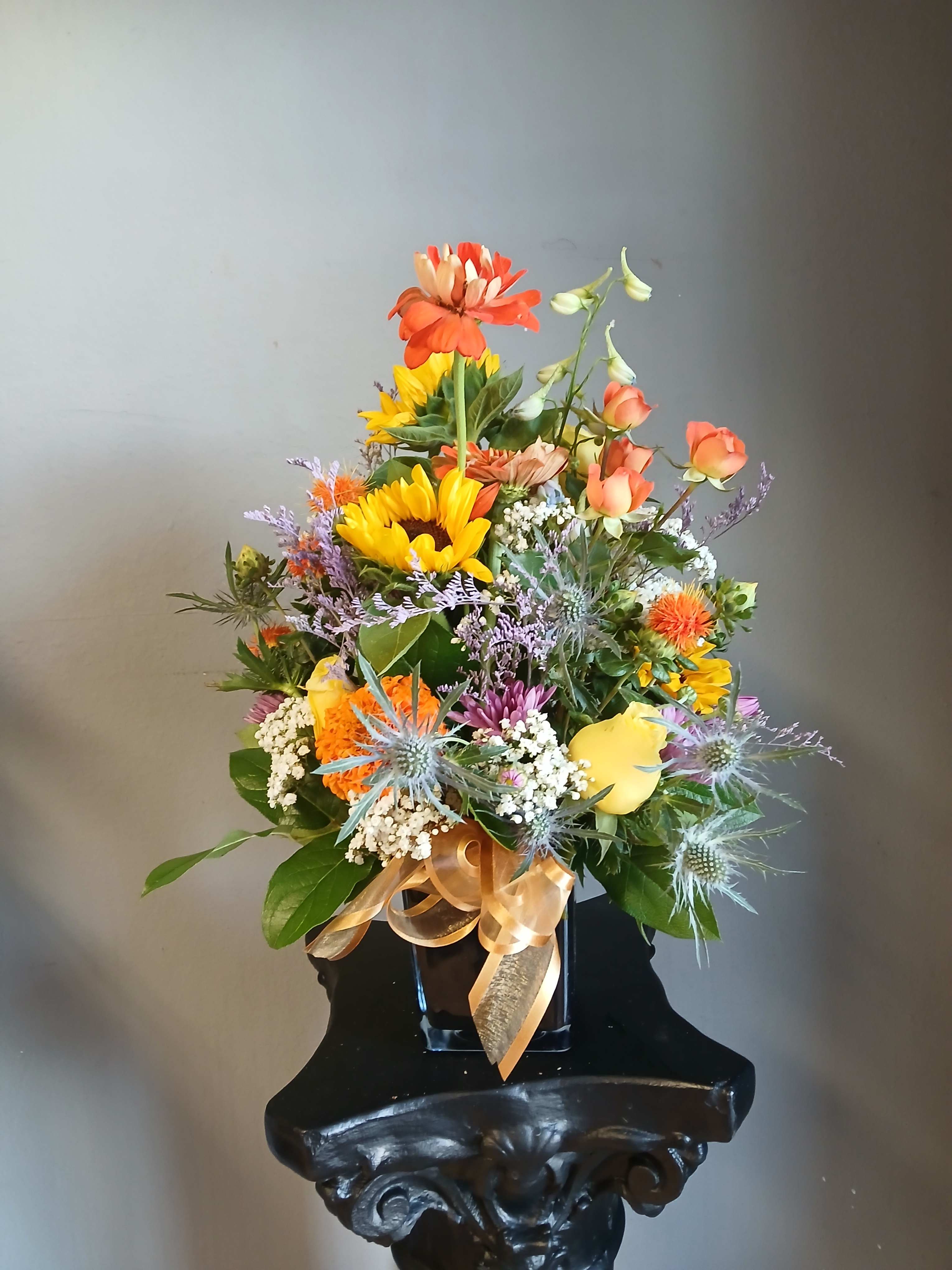 Mixed bouquet in a black vase with orange, yellow, and purple flowers