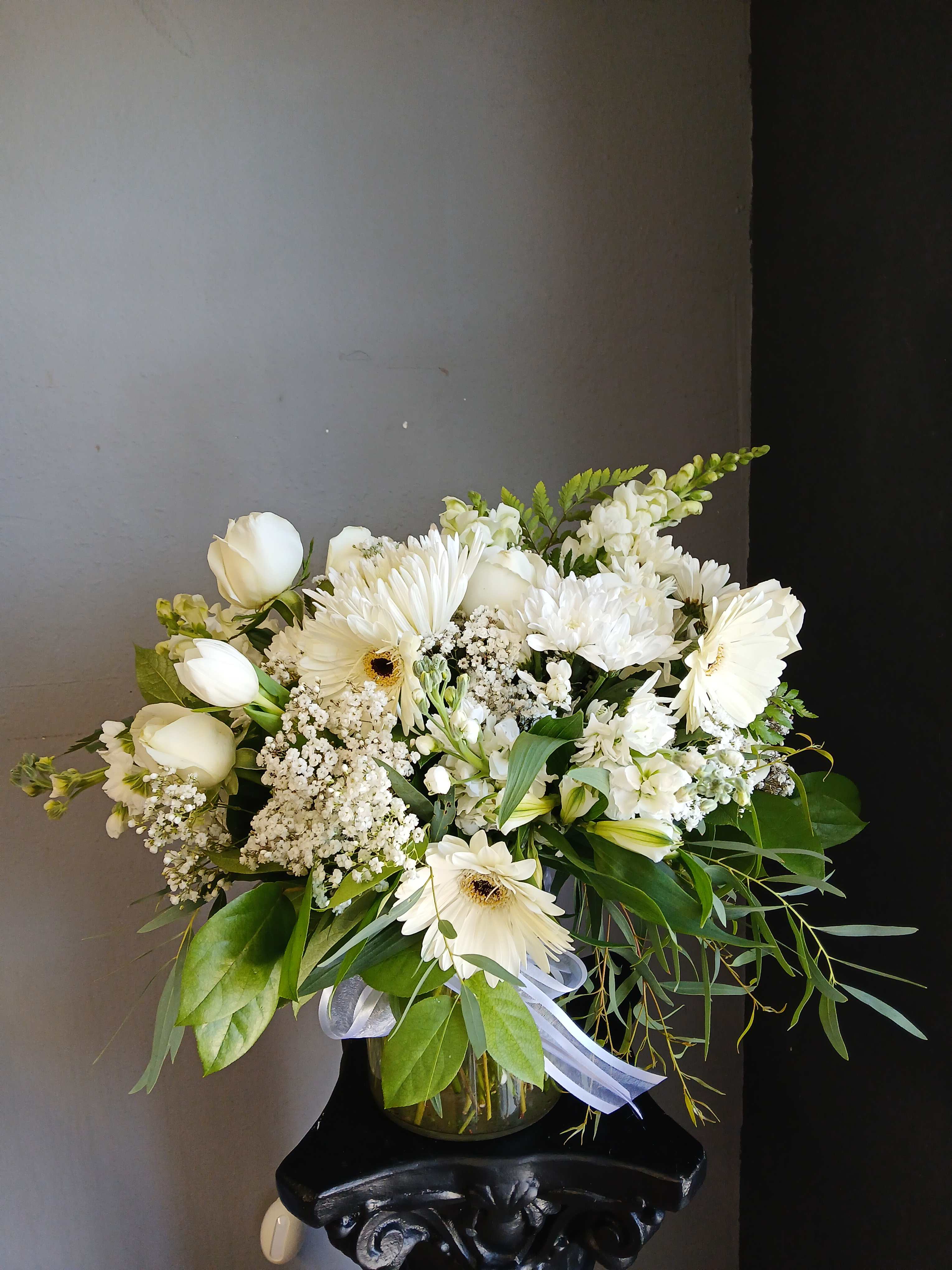 White mixed bouquet in a glass vase with gerbera daisies and tulips