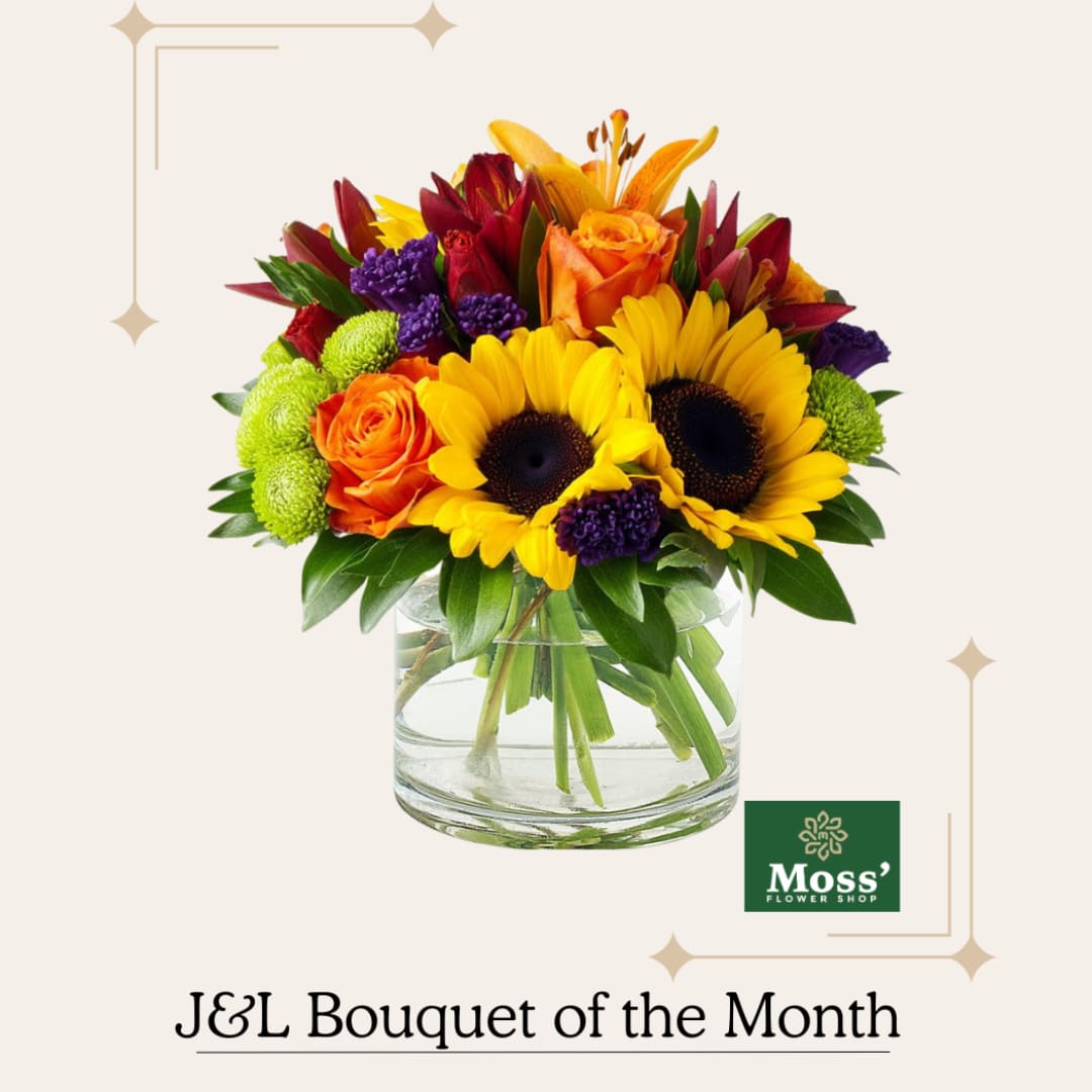 Mixed bouquet of sunflowers, roses, and lilies in a clear glass vase