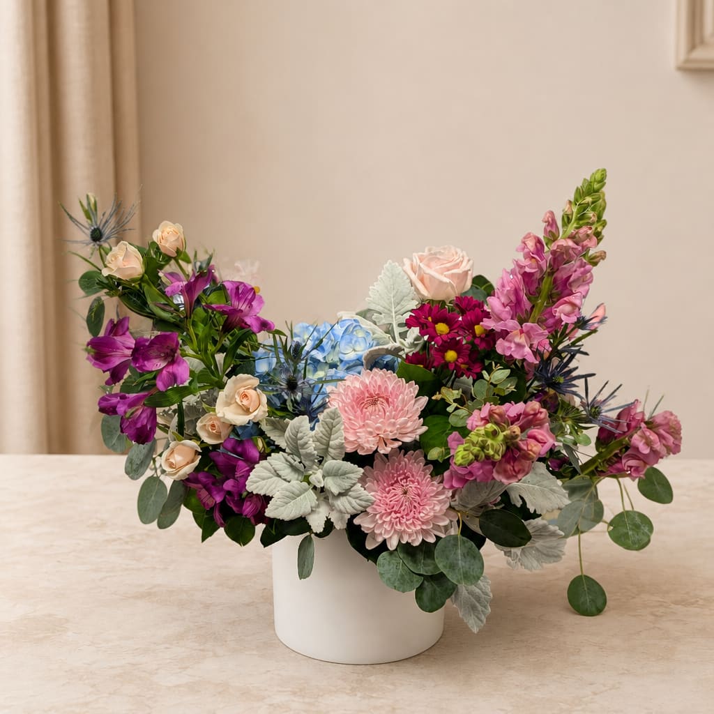 Mixed bouquet in a white vase with pink, purple, and blue flowers