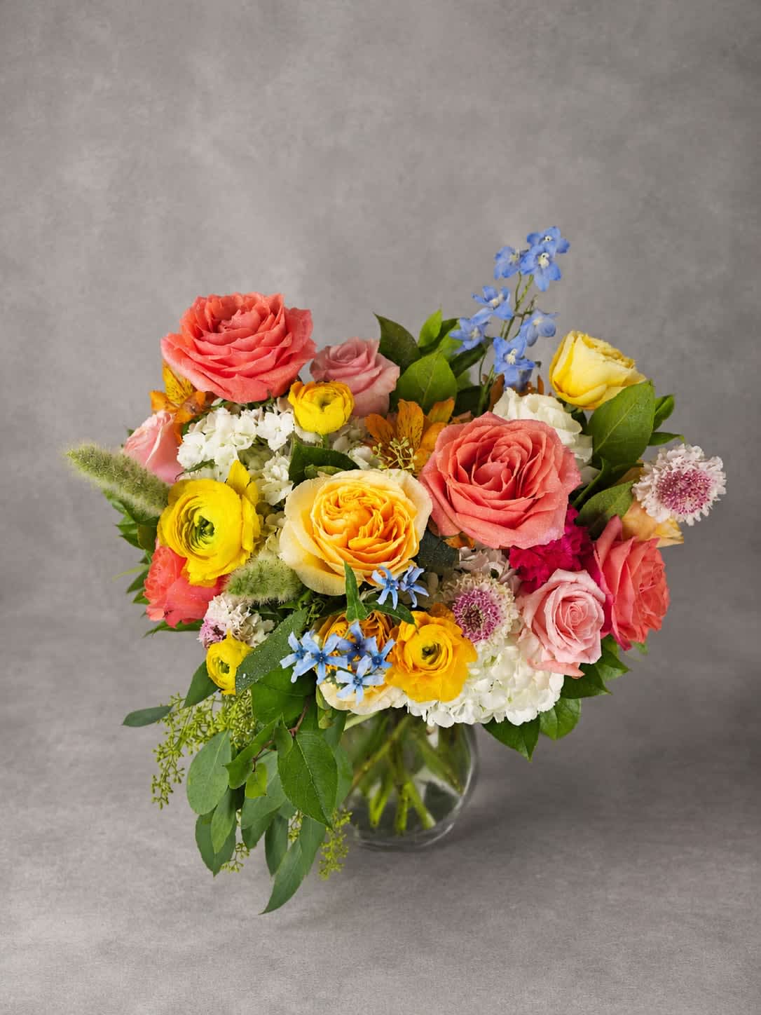 Color Me Happy - Like a garden brought to life by an artist's brush, this arrangement features a colorful blend of roses, ranunculus, hydrangea, and seasonal flowers. Soft pastels mingle with vibrant pops of color to create a design that's playful, elegant, and unforgettable.